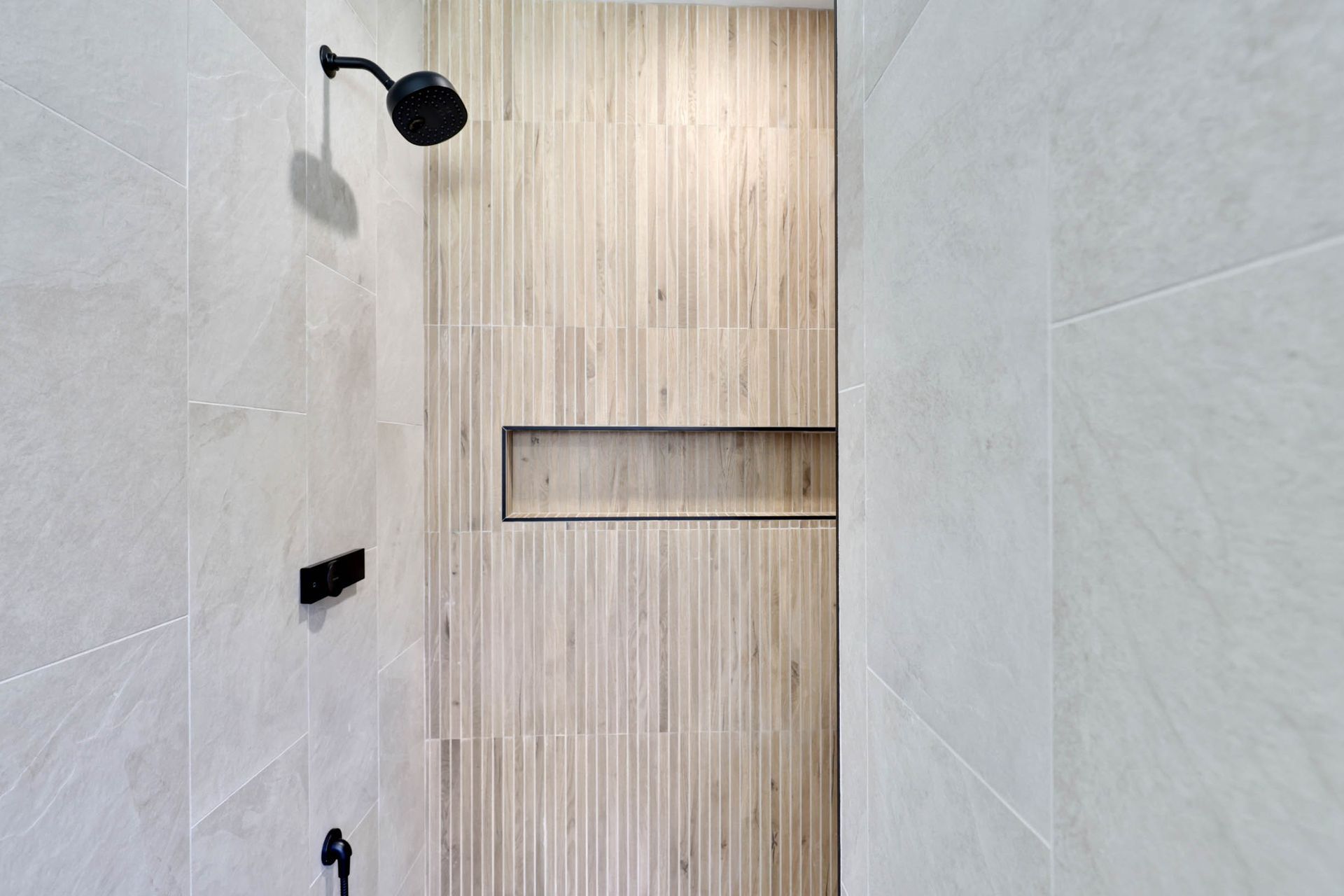 A shower with a wooden wall and a black shower head.