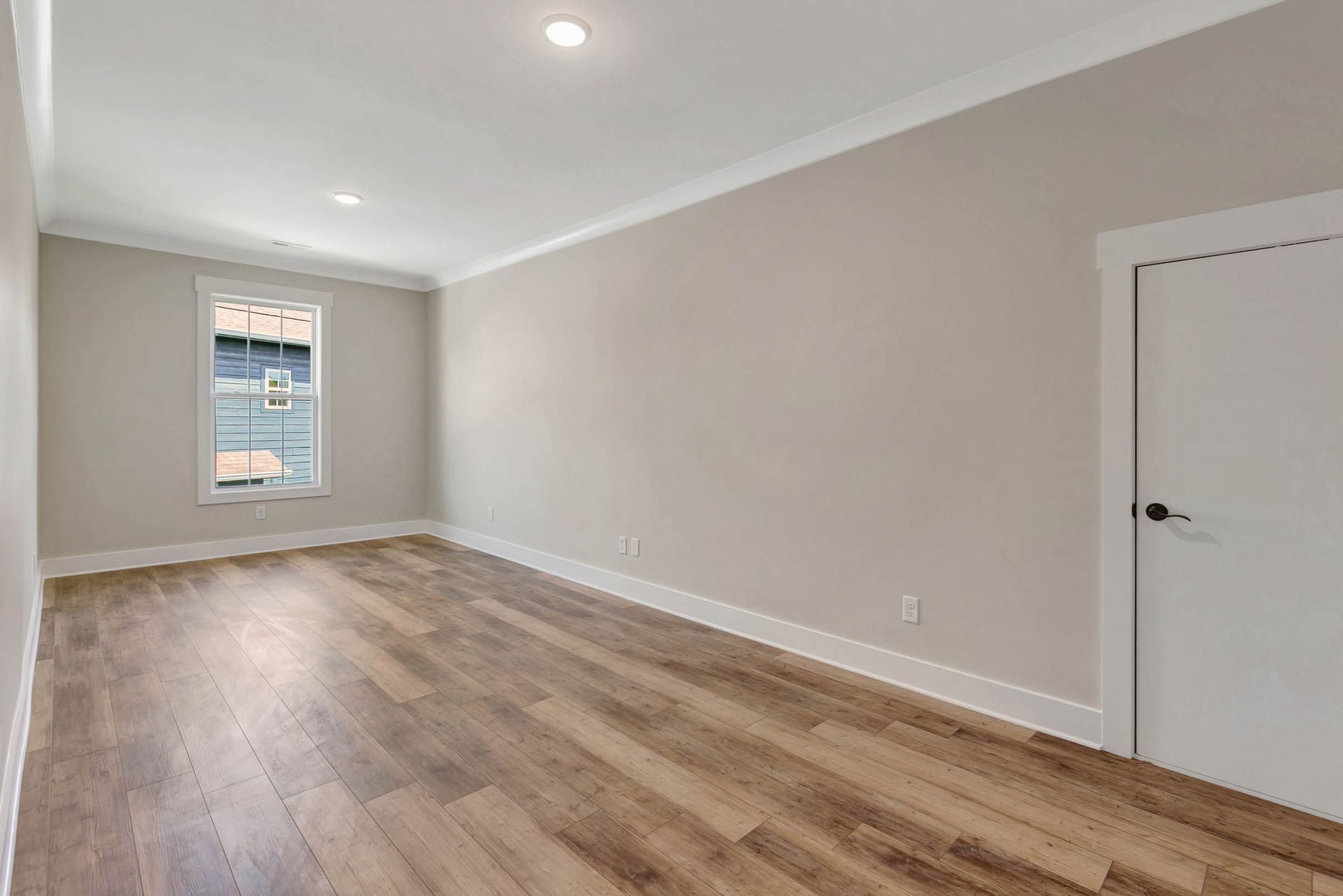 An empty room with hardwood floors and a window.
