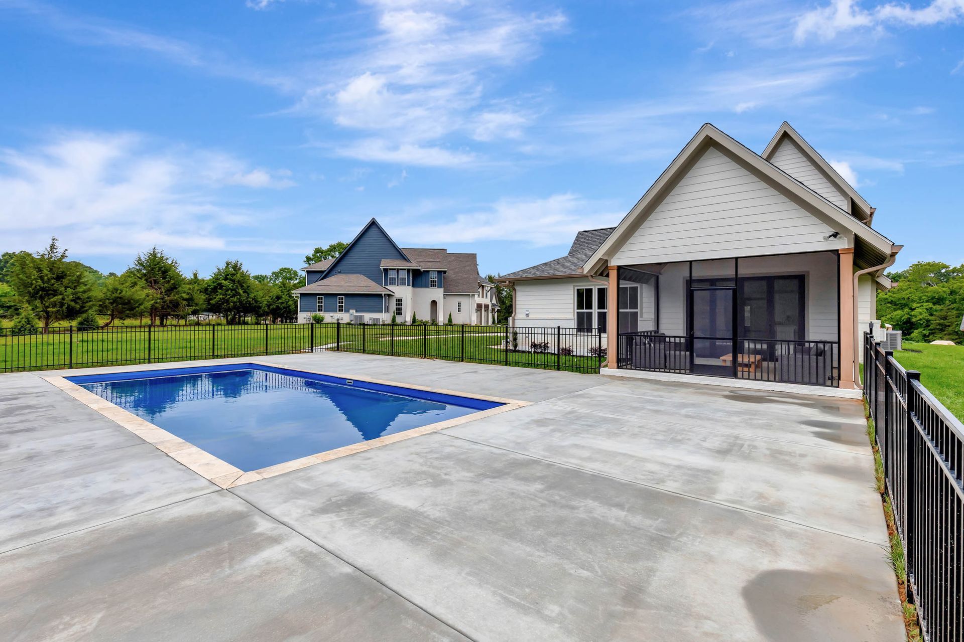 There is a large swimming pool in the backyard of a house.