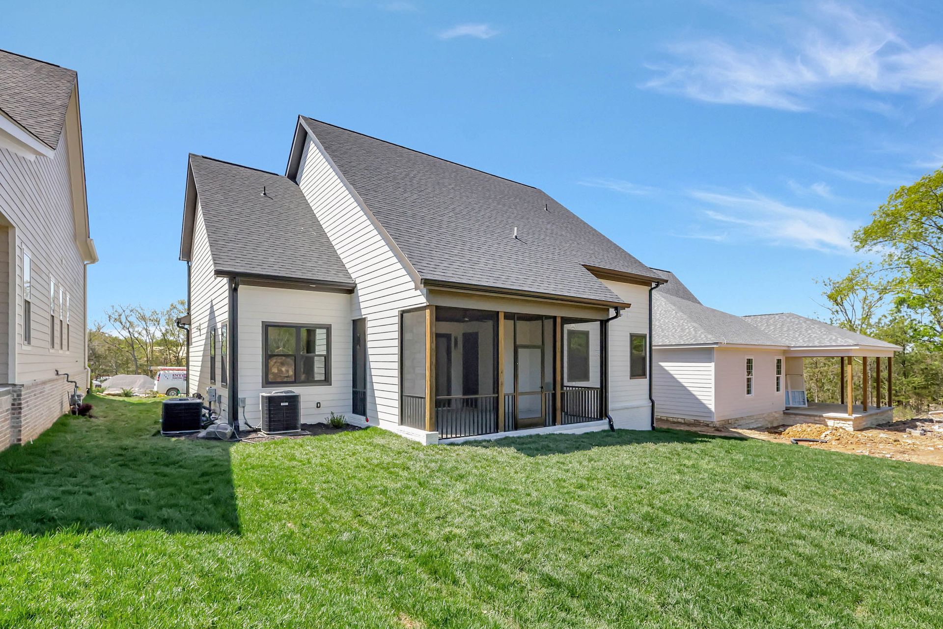 A white house with a gray roof is sitting on top of a lush green lawn.