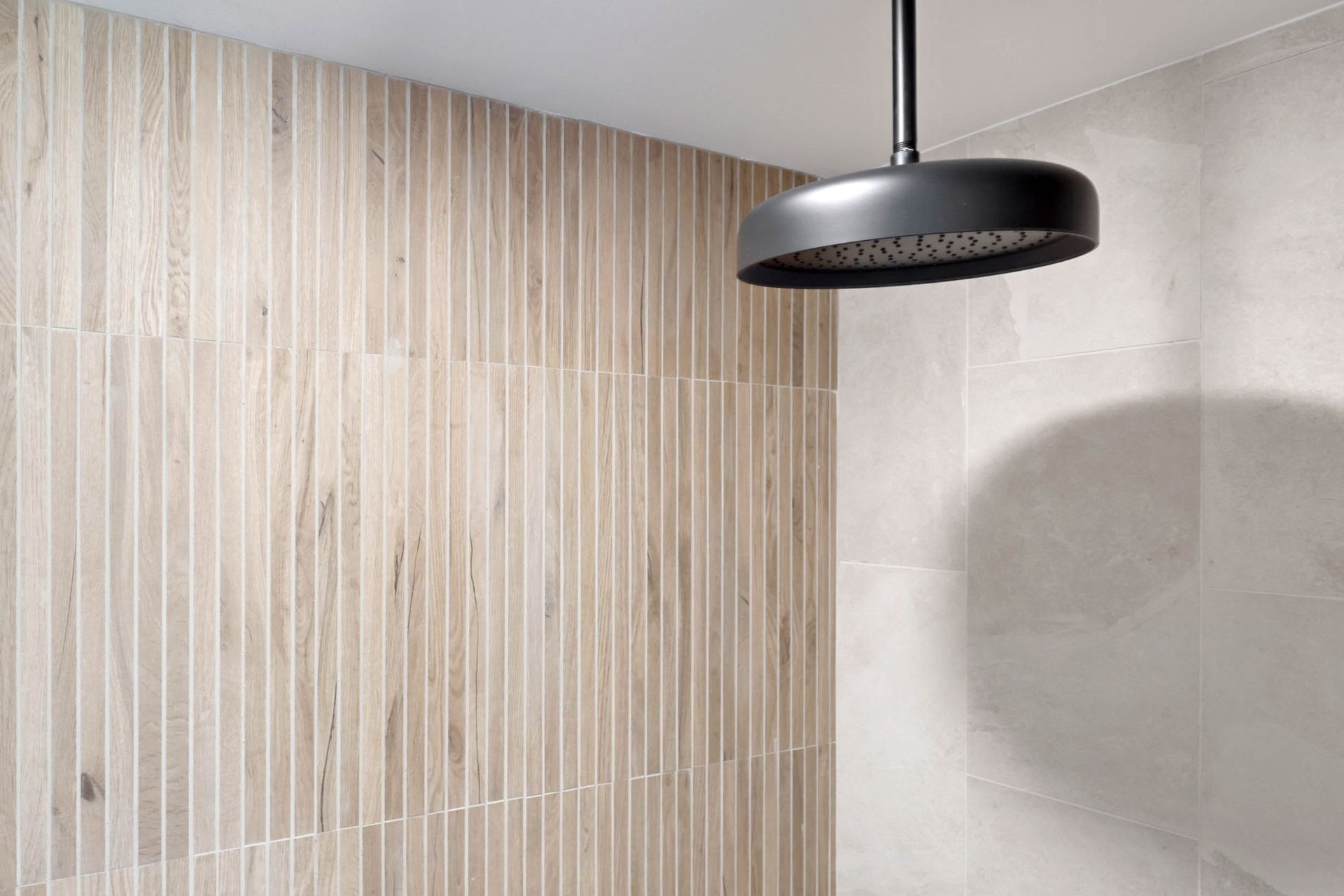 A shower head is hanging from the ceiling in a bathroom.