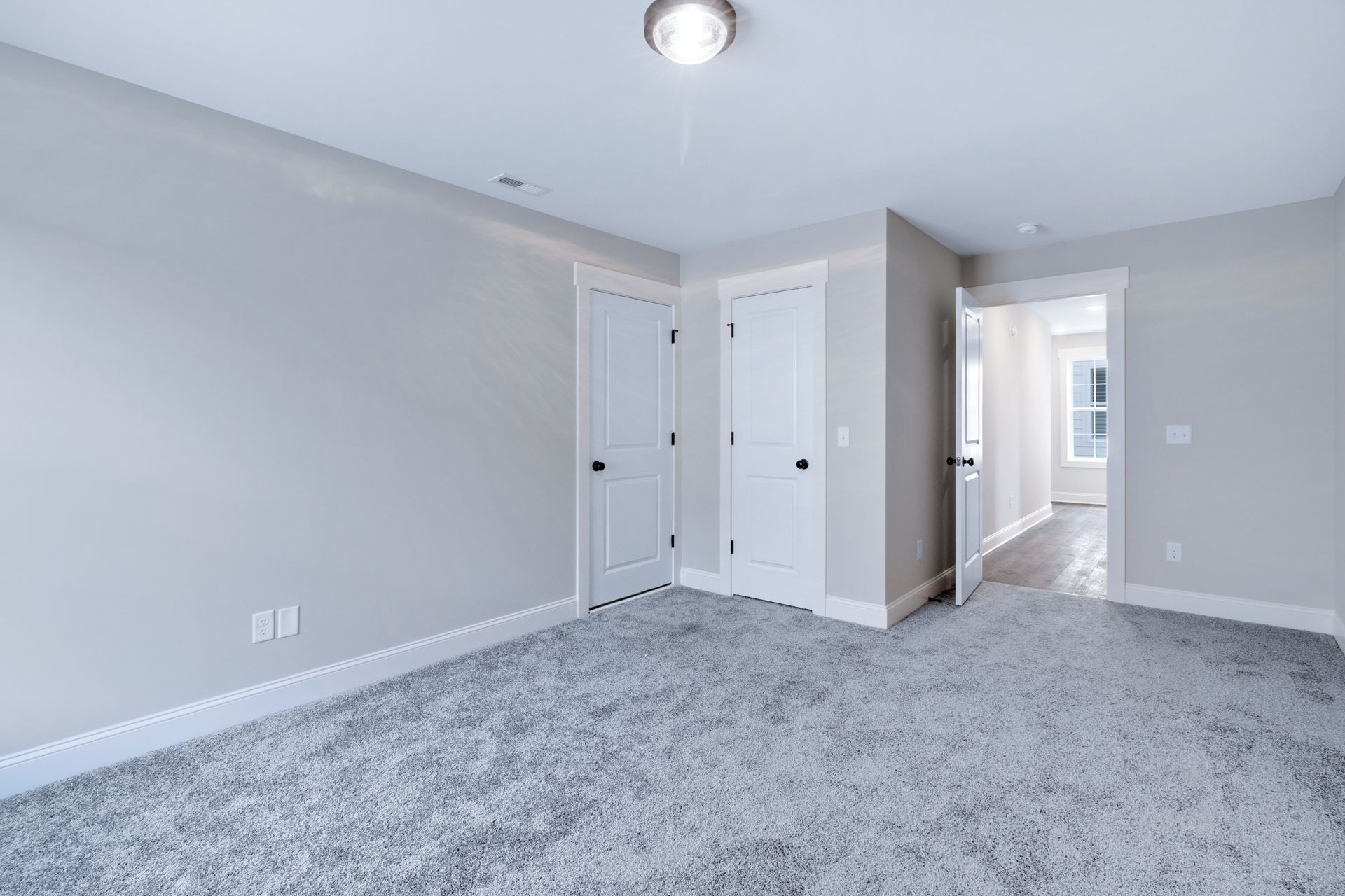 an empty bedroom with a gray carpet and white walls .
