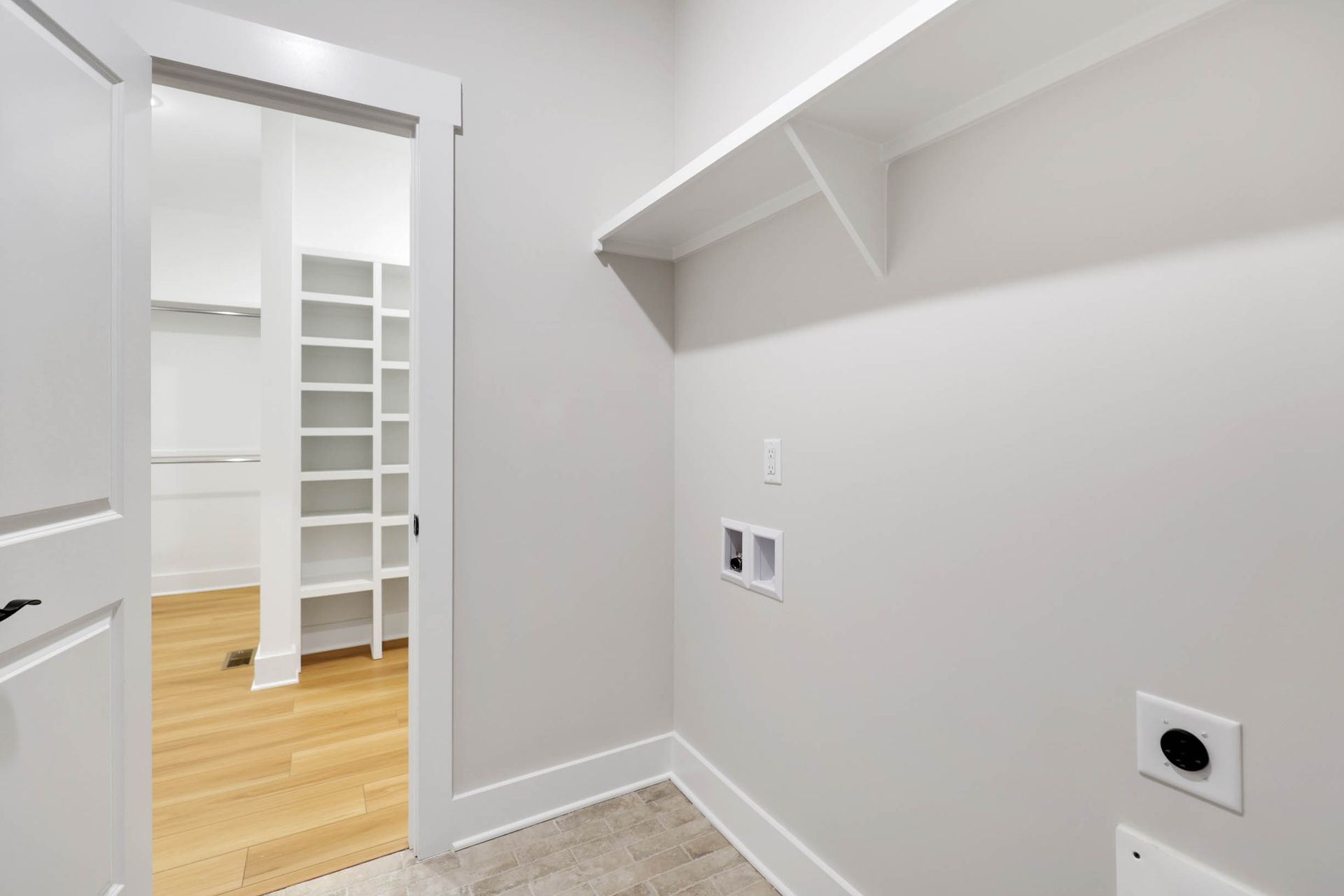 A laundry room with a sliding door leading to a walk in closet.