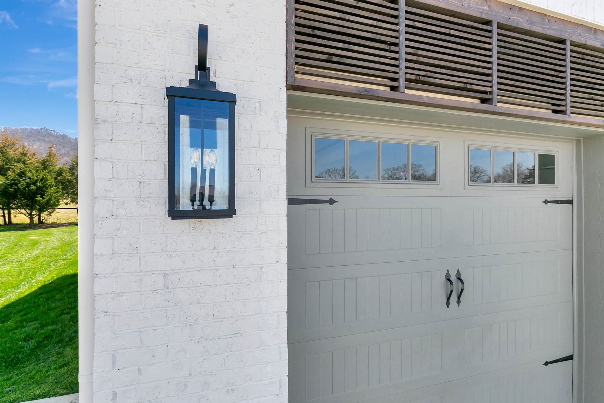 A white garage door with a black lantern on the side of it.