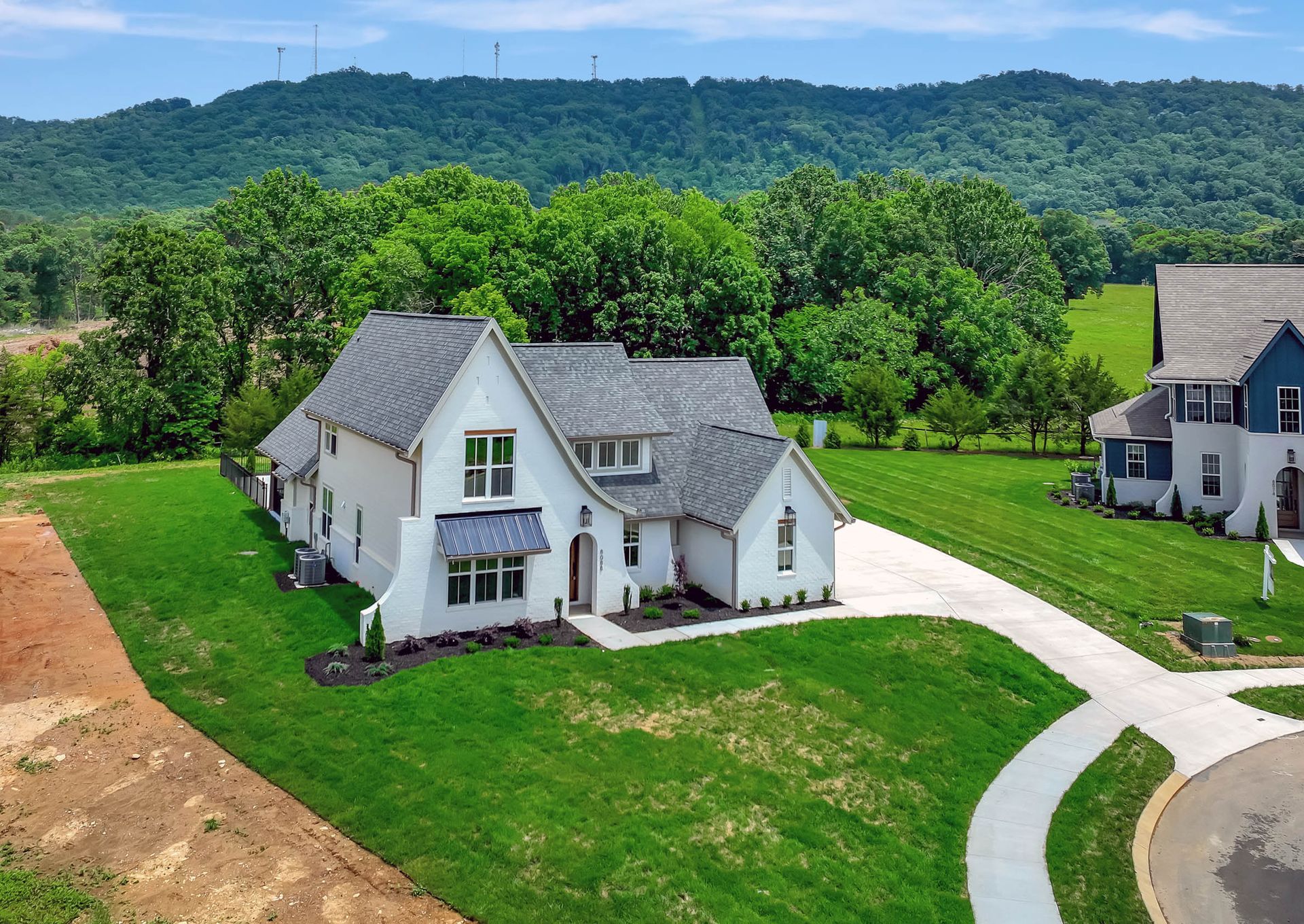 An aerial view of a house with a lot of grass and trees in the background.