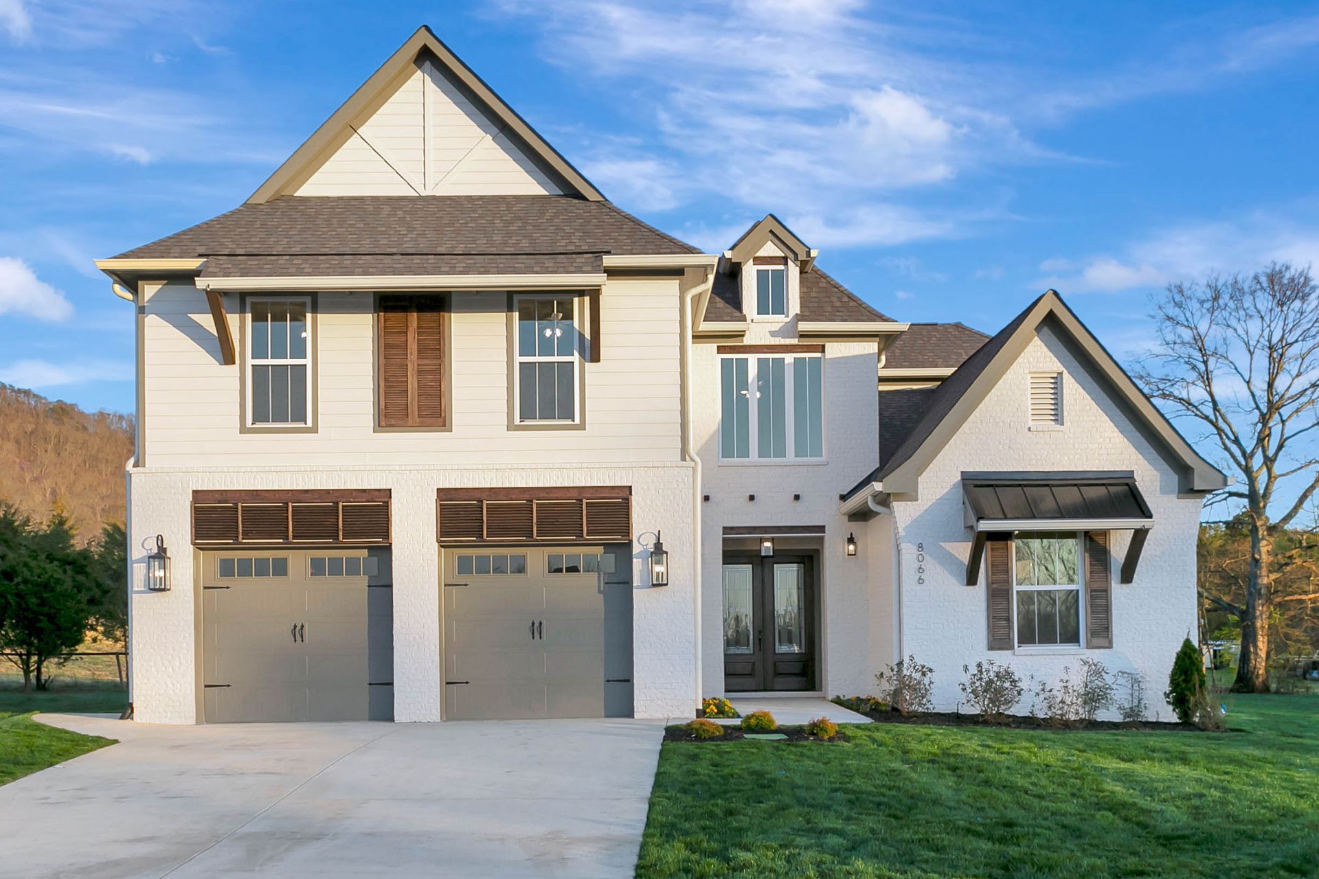 A large white house with two garage doors and a driveway.