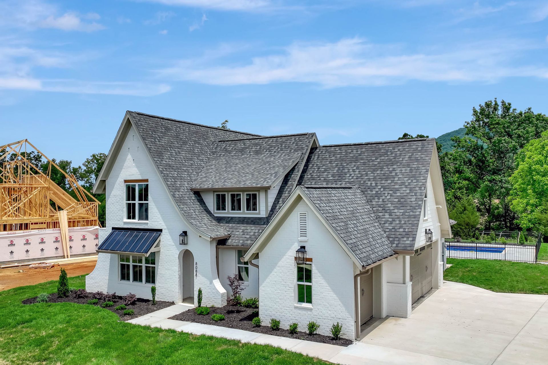 A white house with a gray roof is sitting on top of a lush green field.