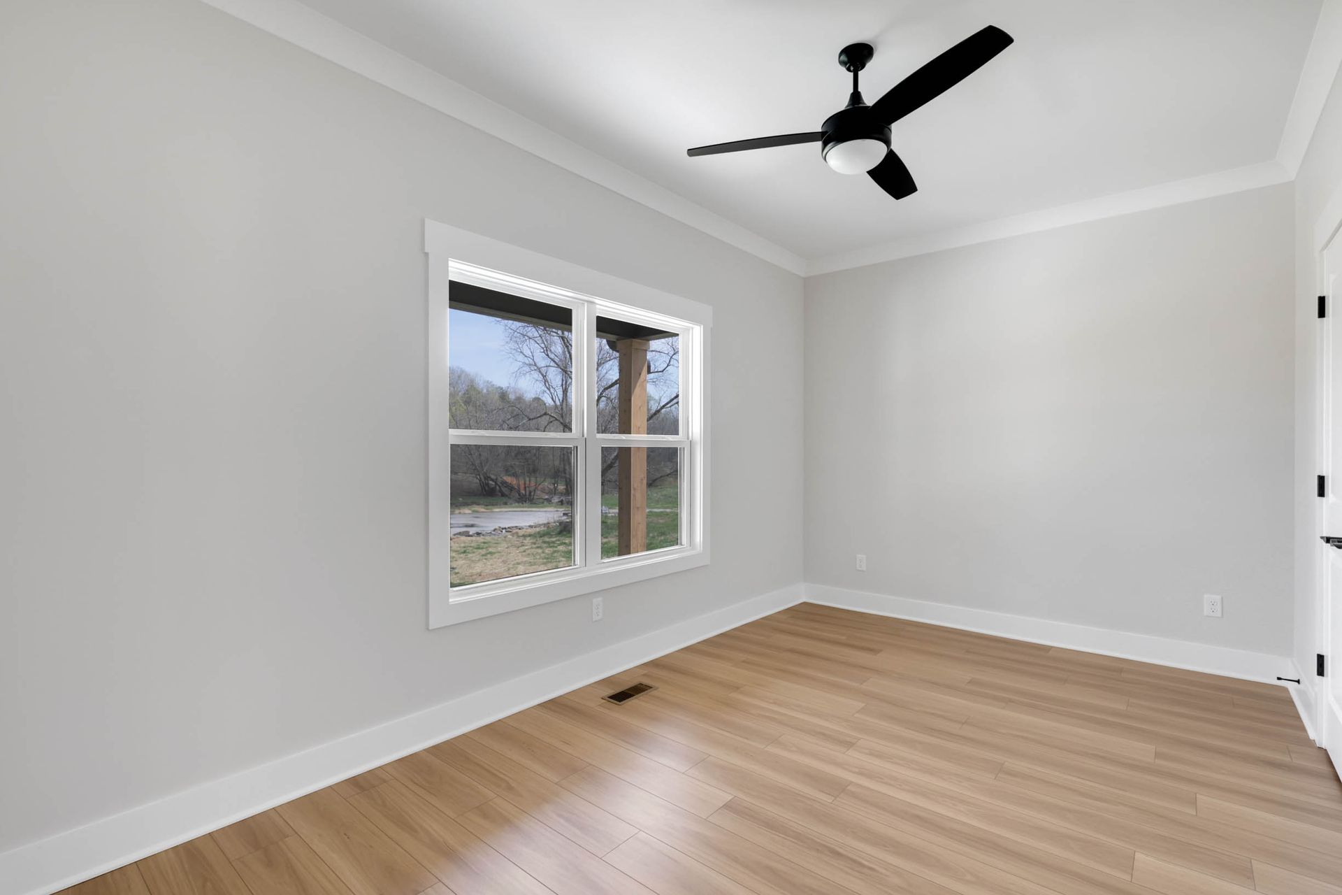 An empty room with a ceiling fan and a window.