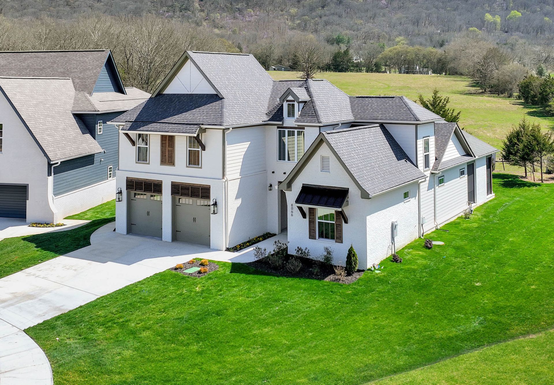 An aerial view of a white house with a gray roof