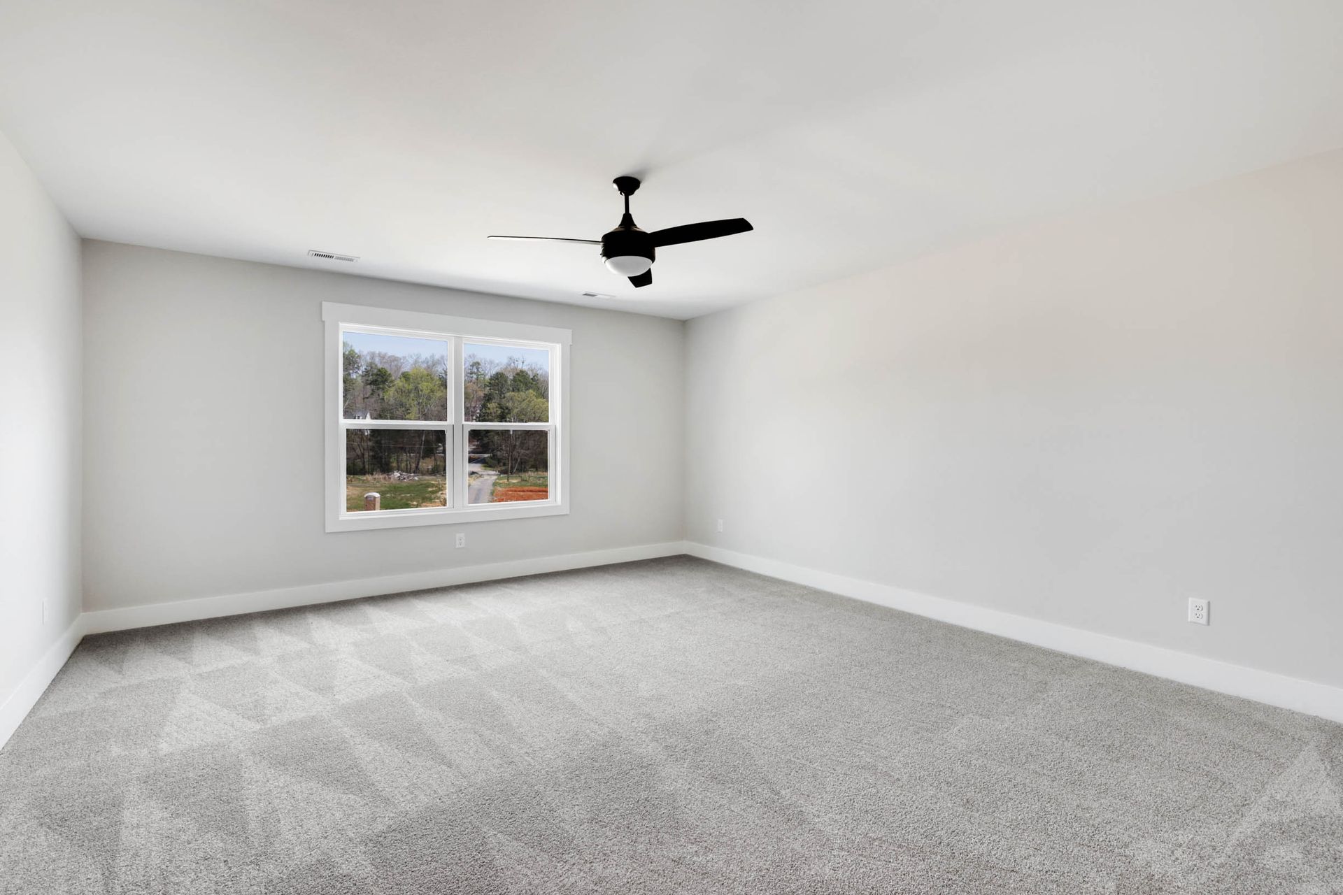 An empty bedroom with a ceiling fan and a window.