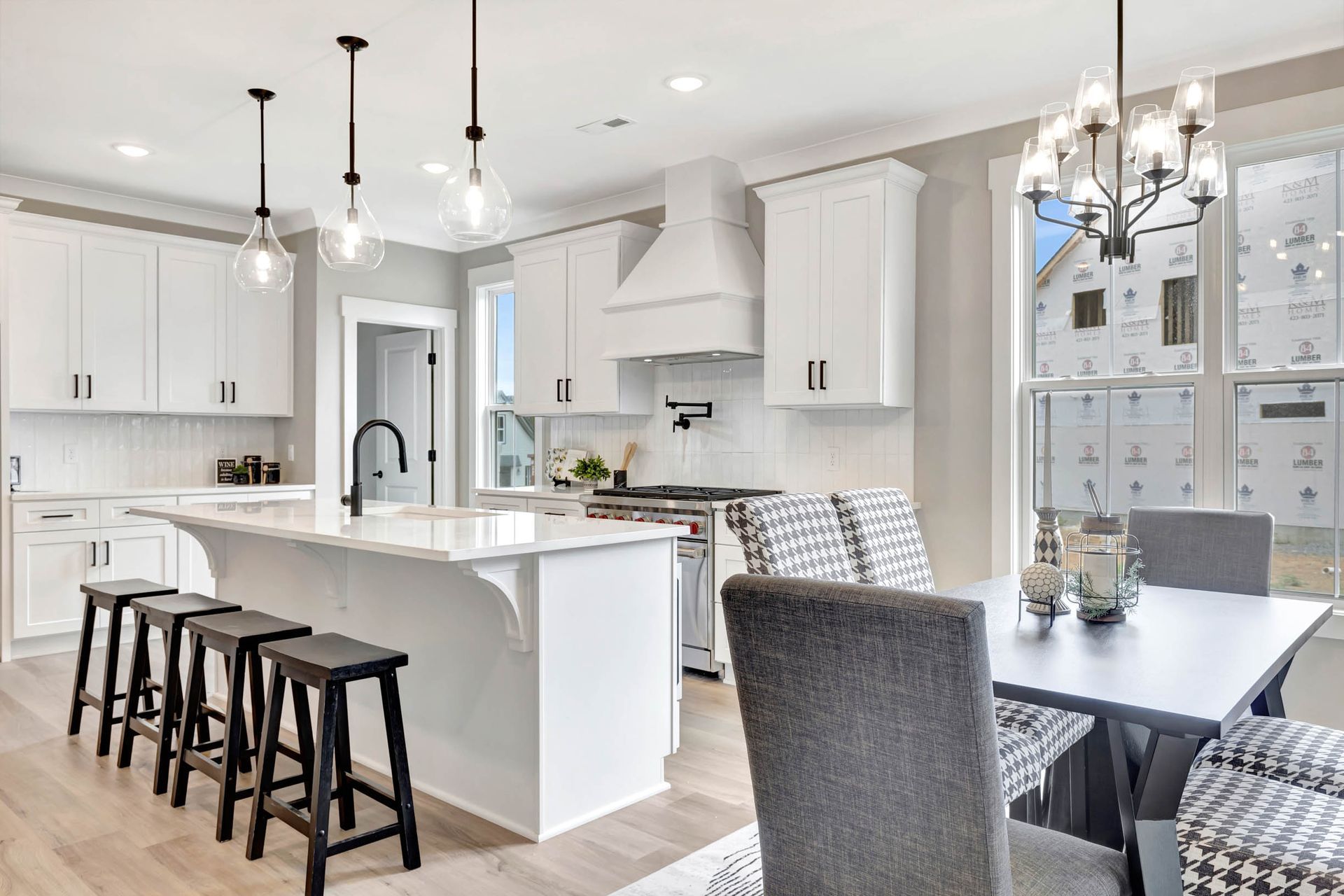 A kitchen with white cabinets , a large island , a table and chairs.