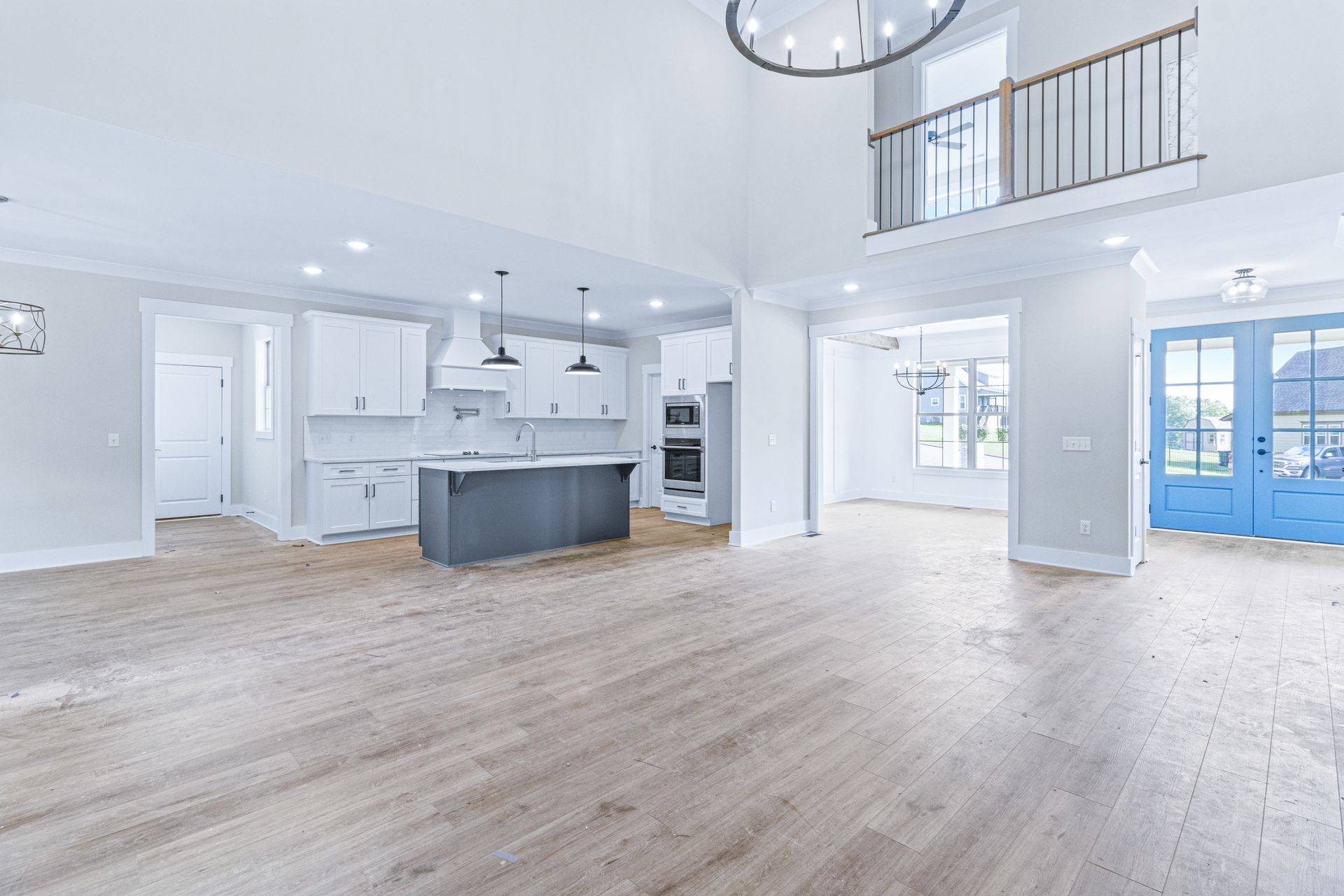 a large empty room with hardwood floors and a kitchen .
