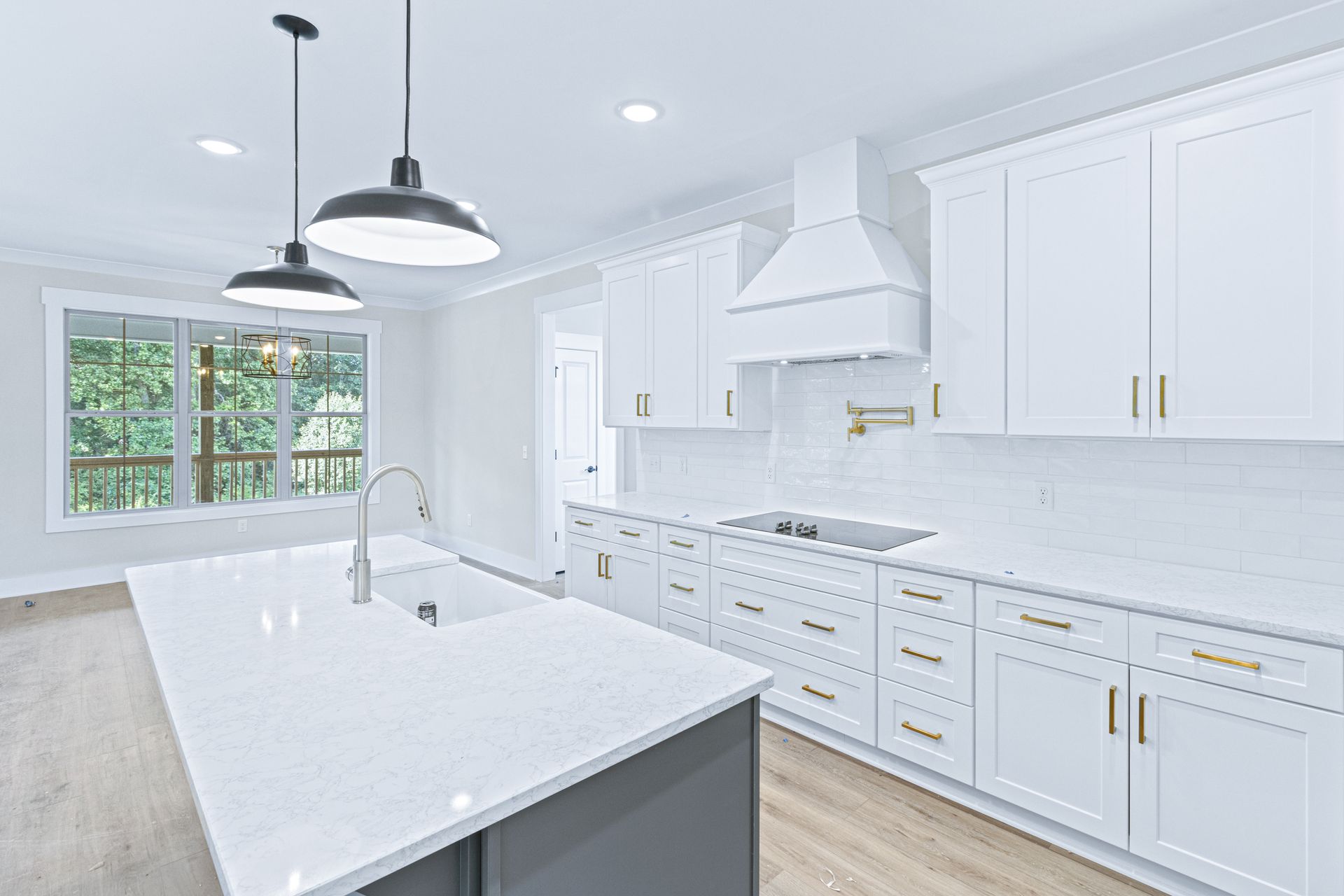 a kitchen with white cabinets , white counter tops , and a large island .
