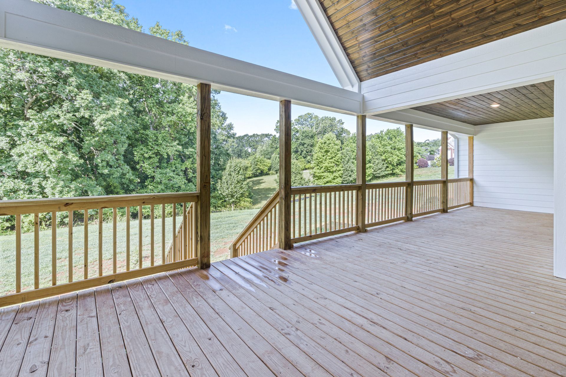 an empty deck with a wooden railing and trees in the background .