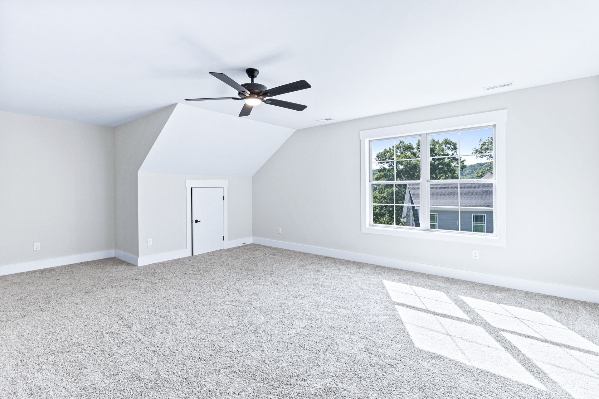 an empty bedroom with a ceiling fan and a window .