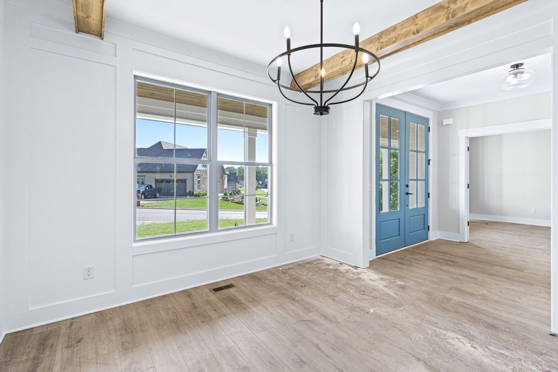 an empty living room with hardwood floors and a chandelier .
