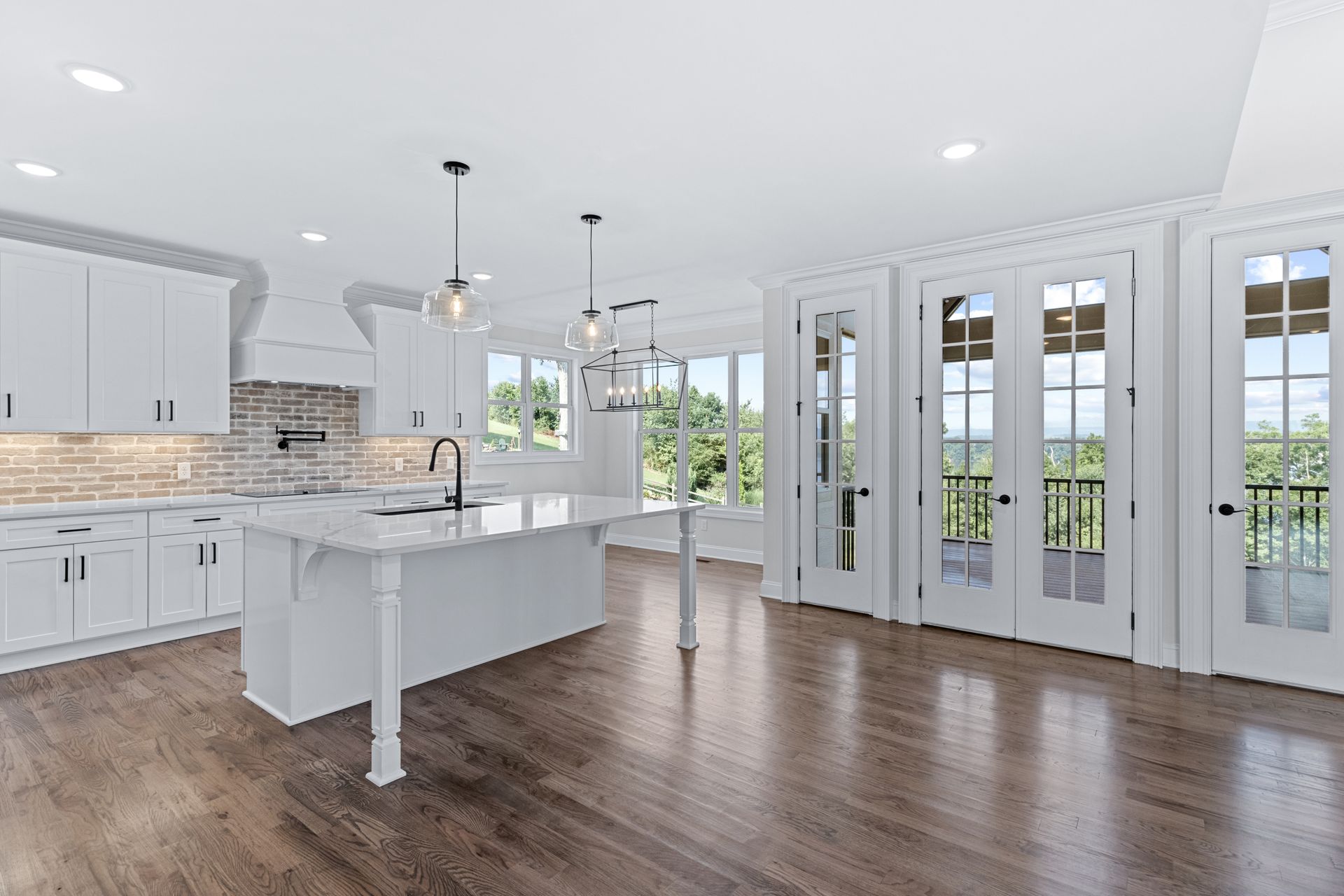 an empty kitchen with white cabinets and hardwood floors .