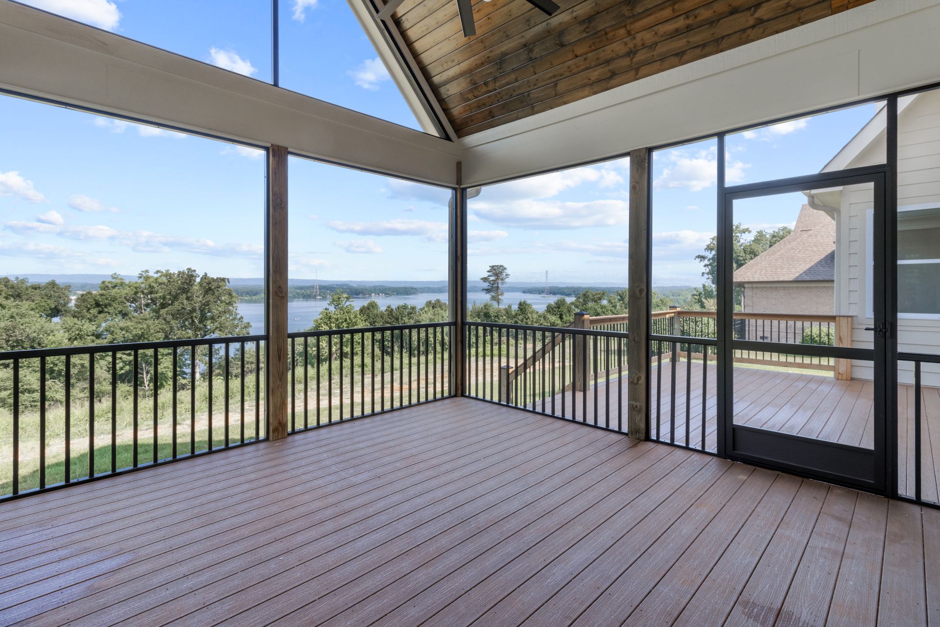 an empty screened in porch with a view of a lake .