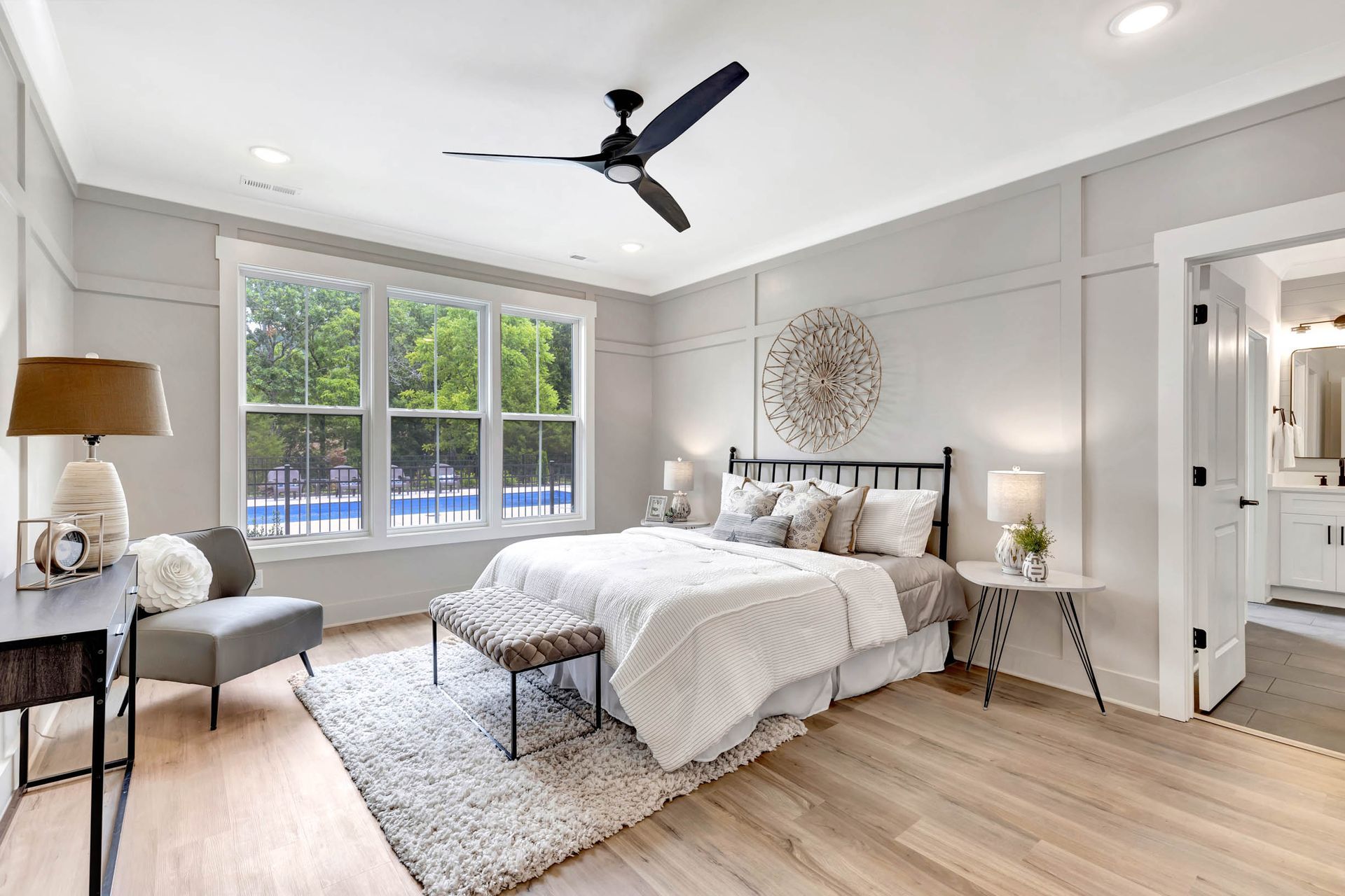 A bedroom with a bed , chair , table and ceiling fan.