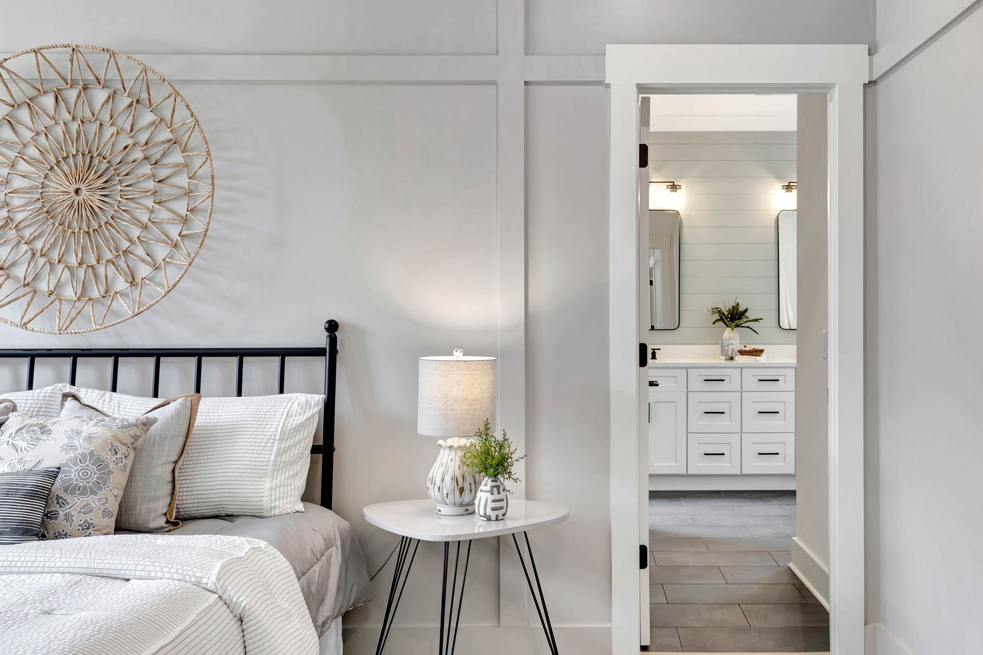 A bedroom with a bed , nightstand , lamp and a door leading to a bathroom.