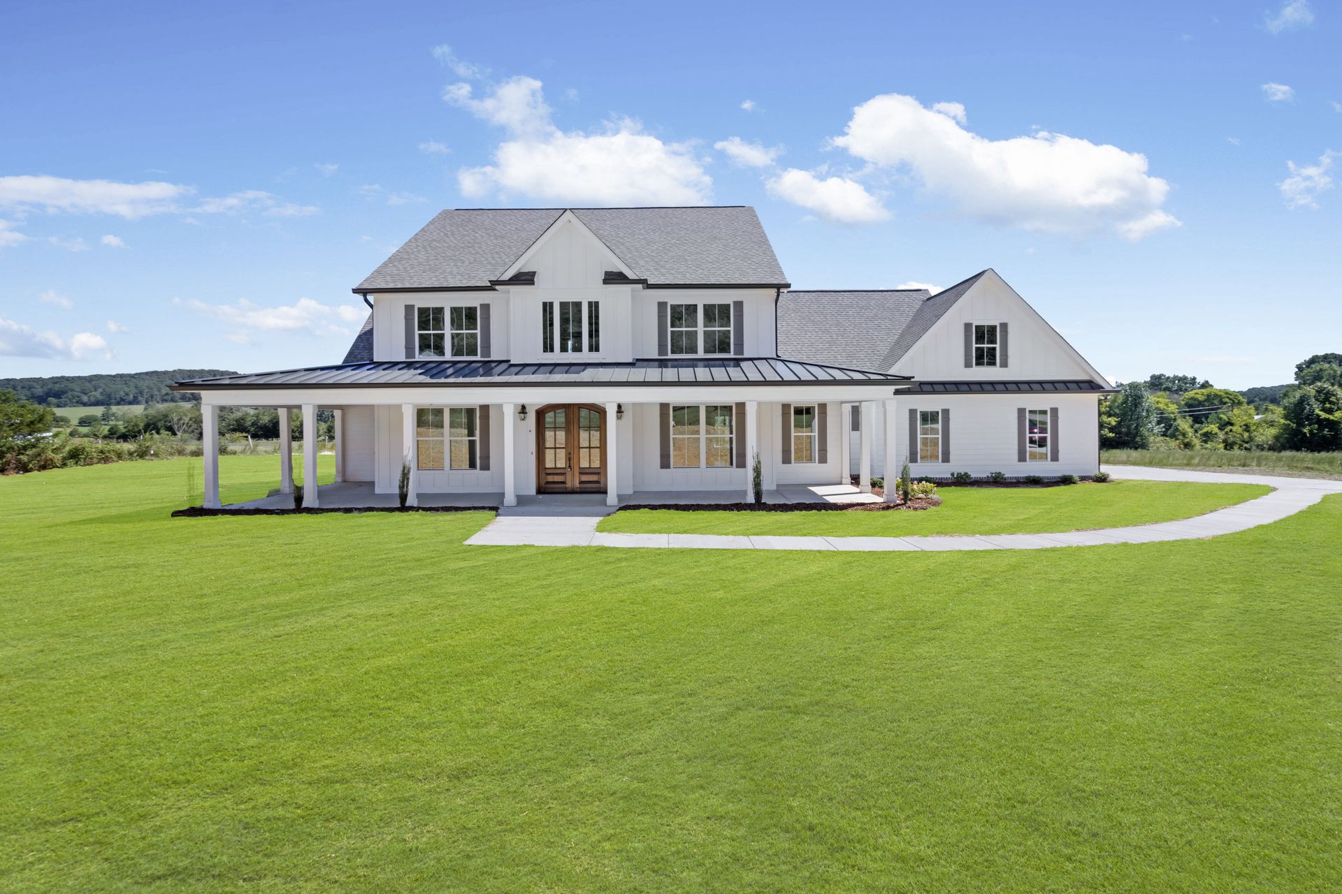 a large white house is sitting on top of a lush green field .