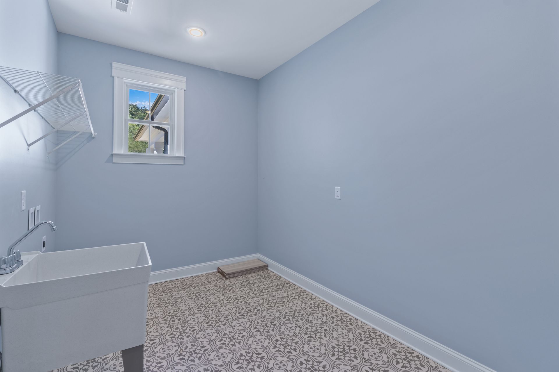 an empty laundry room with a sink and a window .