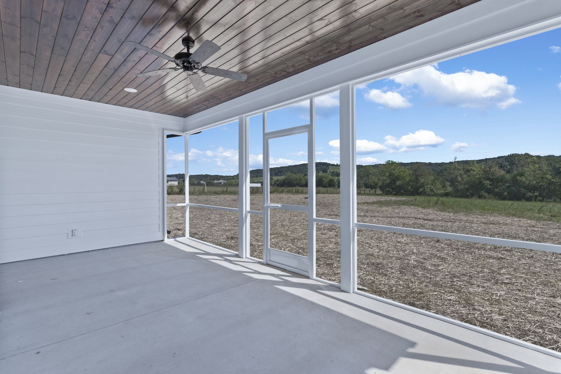 an empty room with a lot of windows and a ceiling fan .