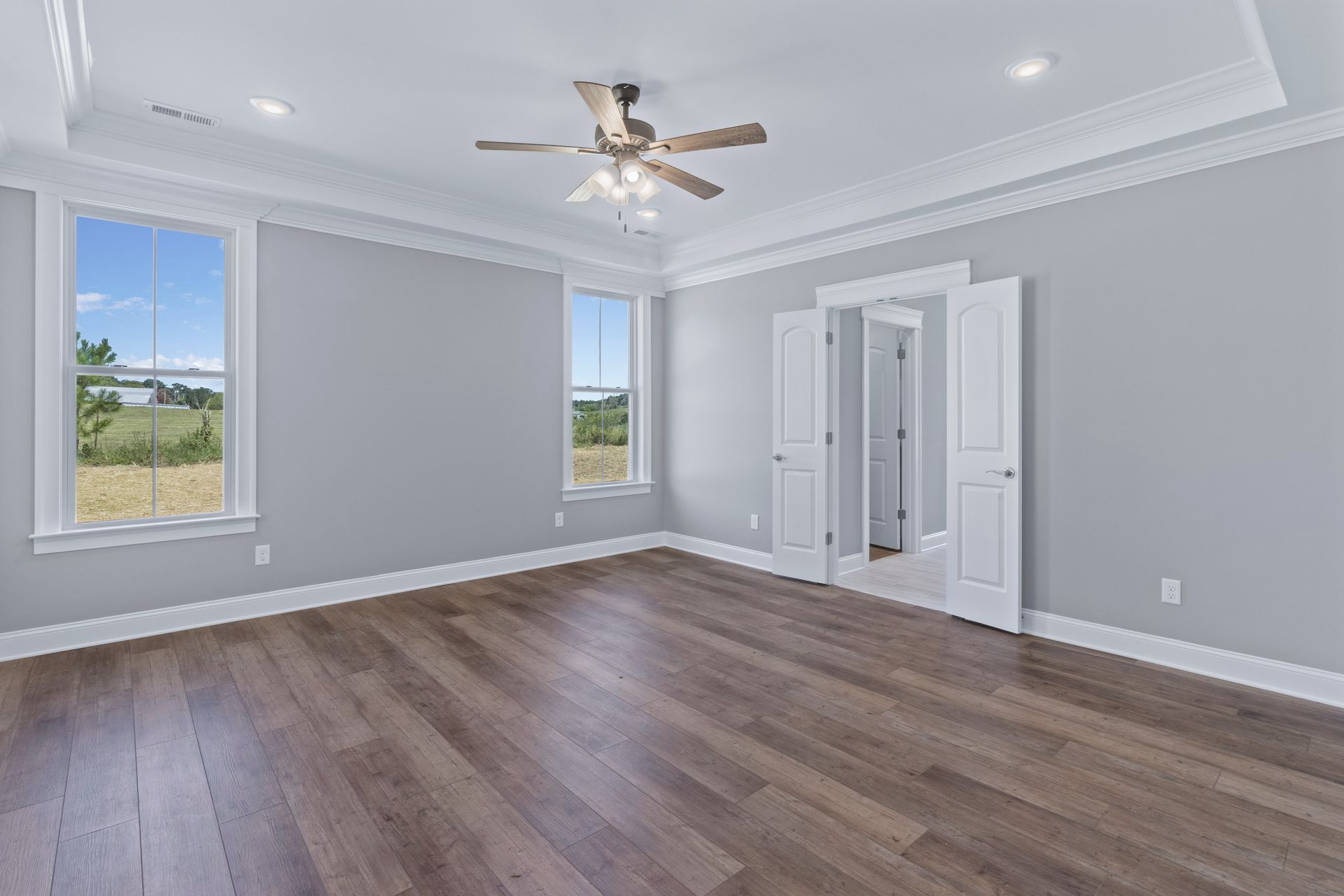 a large empty room with hardwood floors and a ceiling fan .