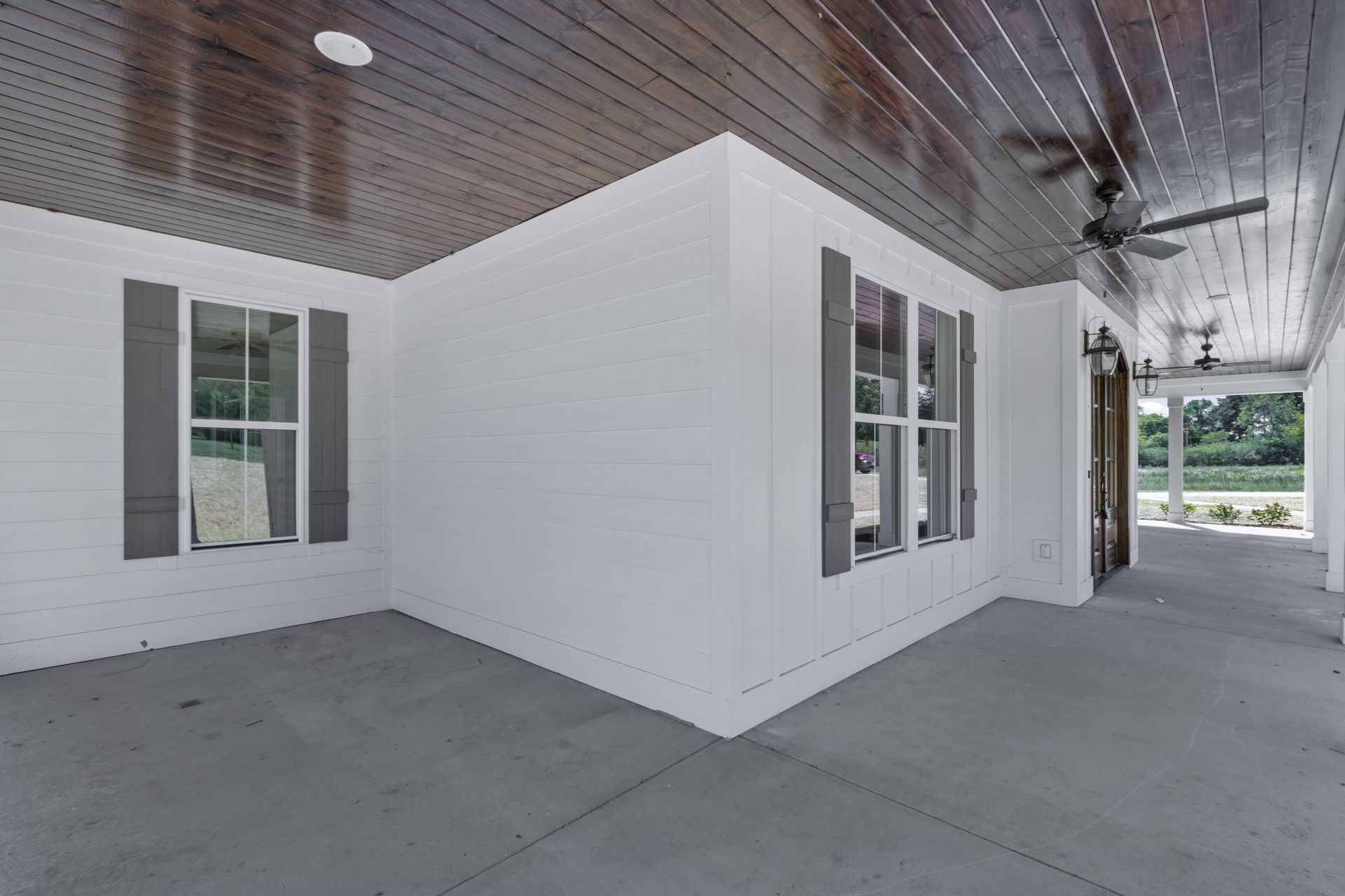 a white house with a covered porch and a ceiling fan .