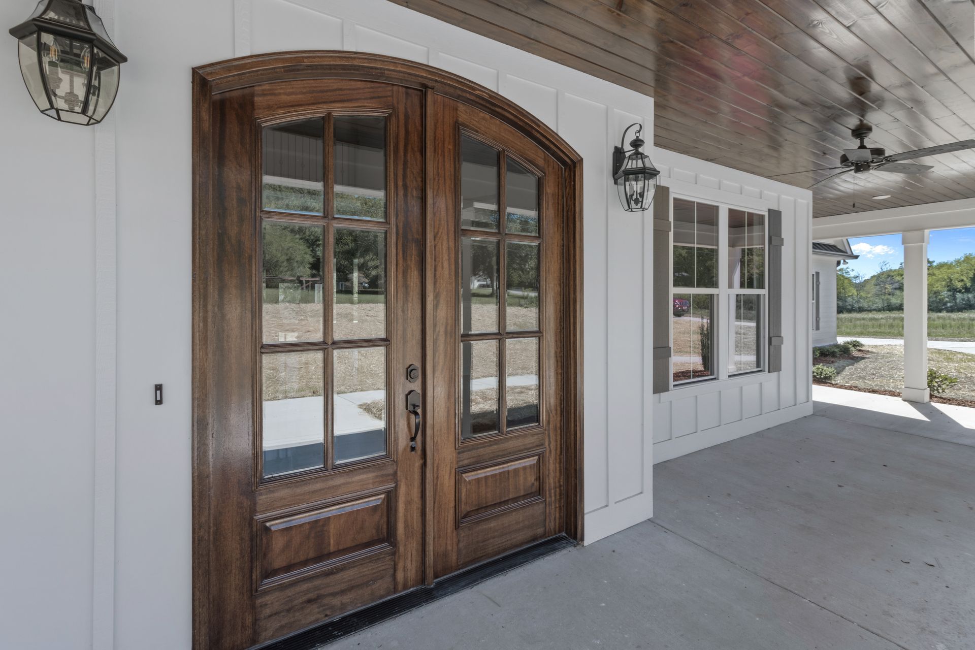a large wooden door with a lot of windows on a white house .