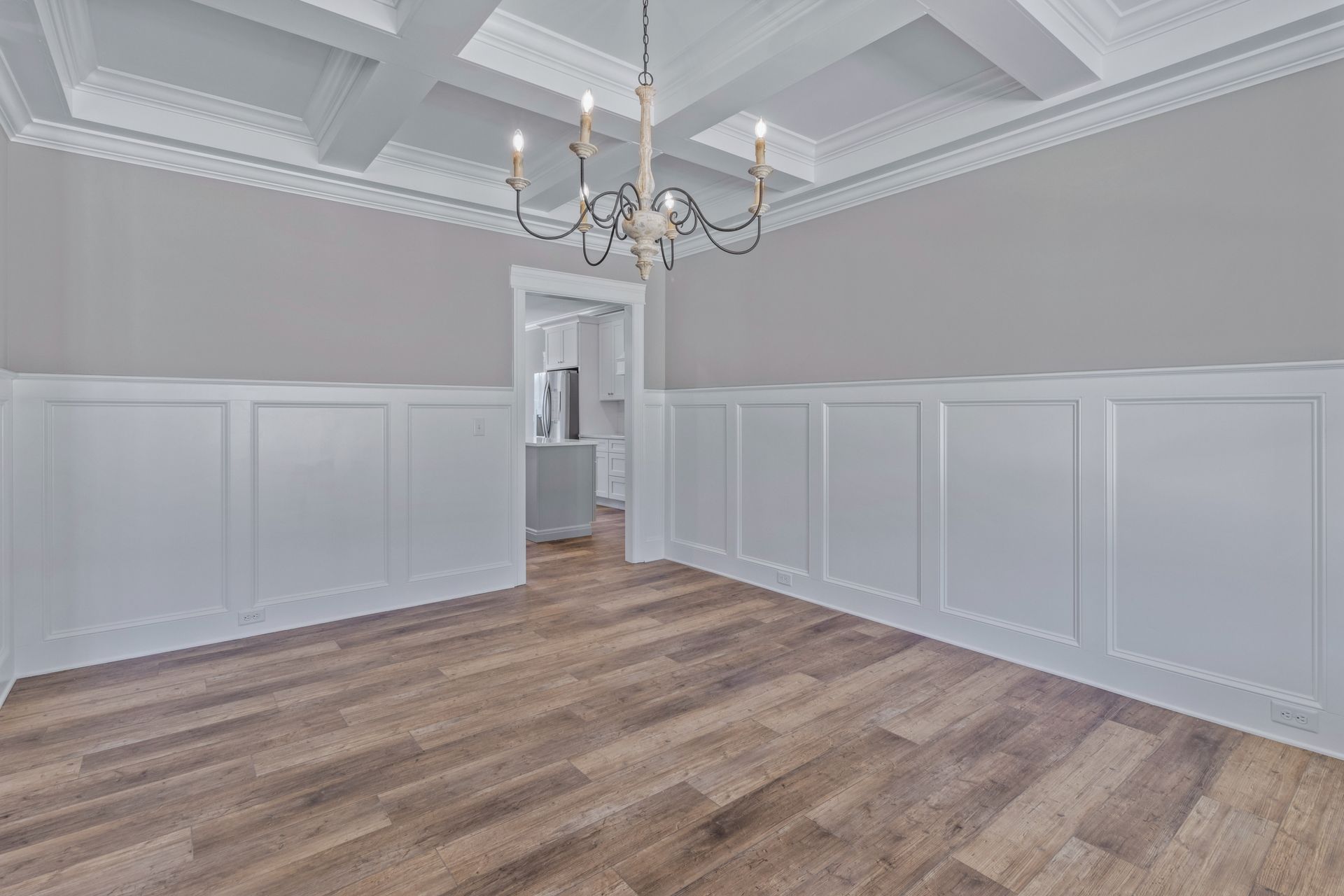 an empty dining room with hardwood floors and a chandelier .