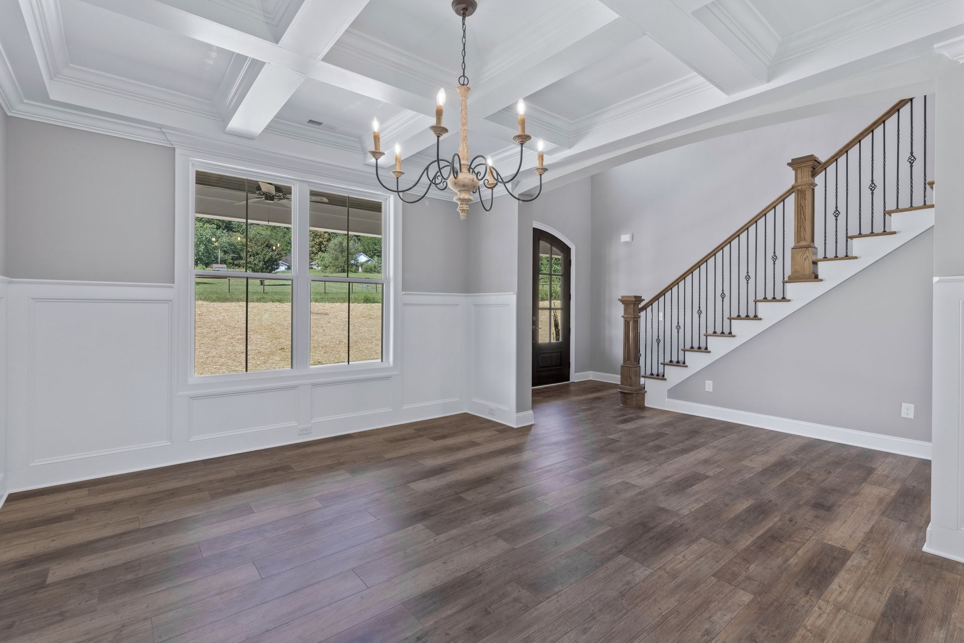 an empty living room with hardwood floors and a staircase .