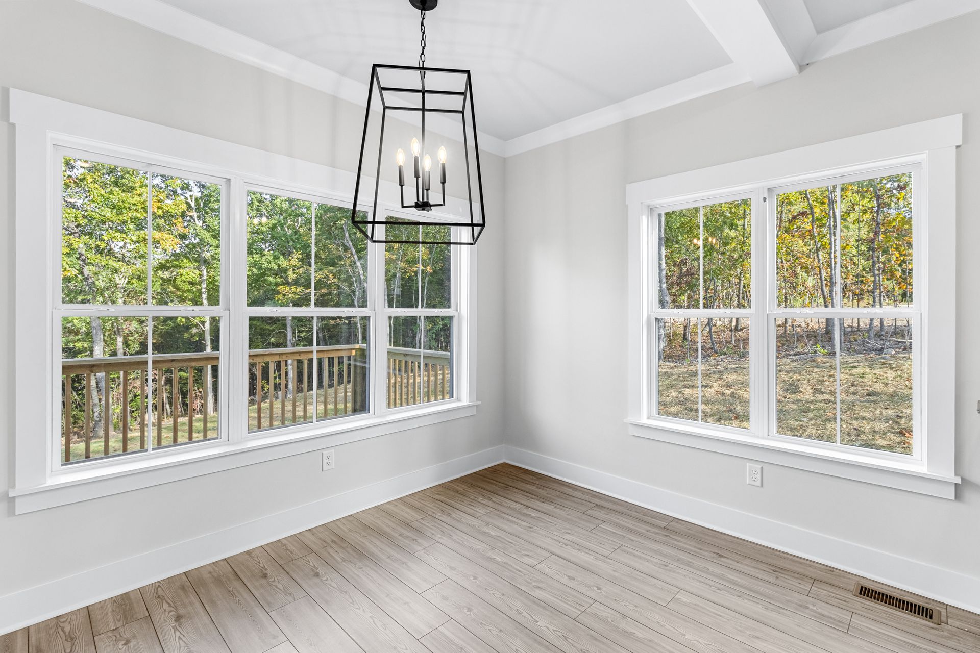 An empty room with lots of windows and a chandelier hanging from the ceiling.