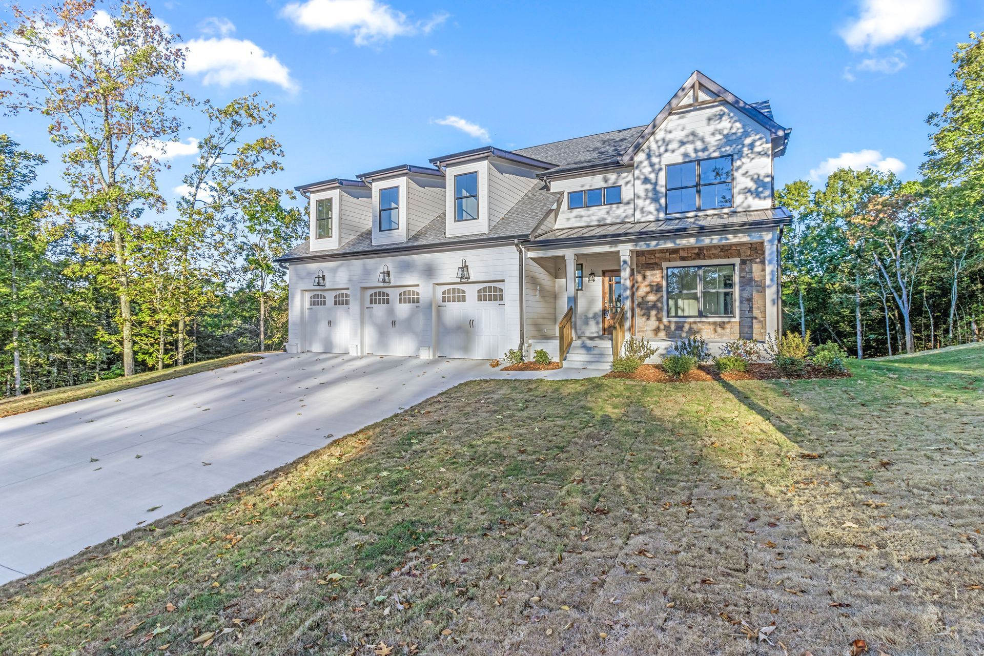a large white house with a driveway leading to it is surrounded by trees .