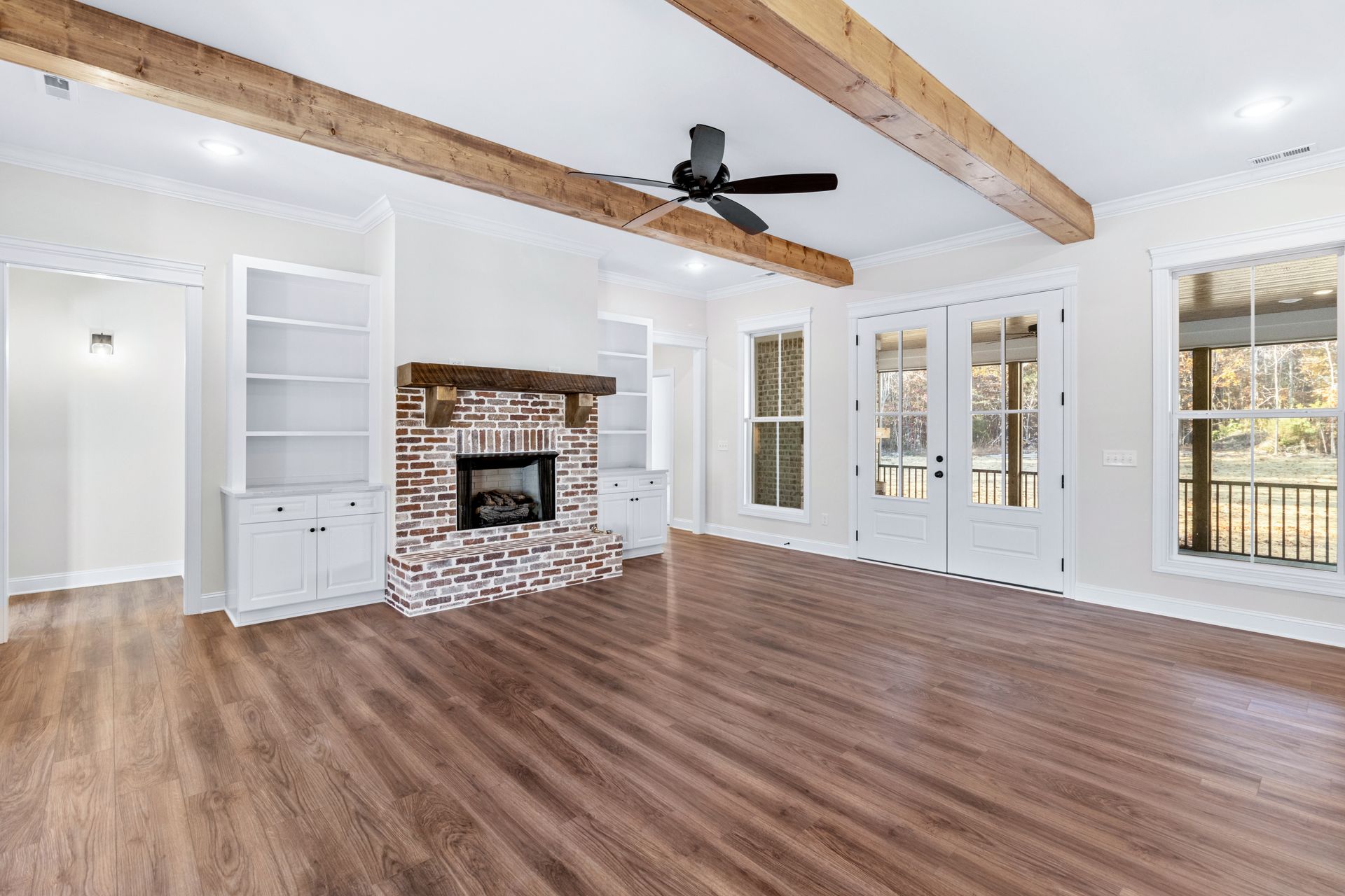 An empty living room with a fireplace and a ceiling fan.