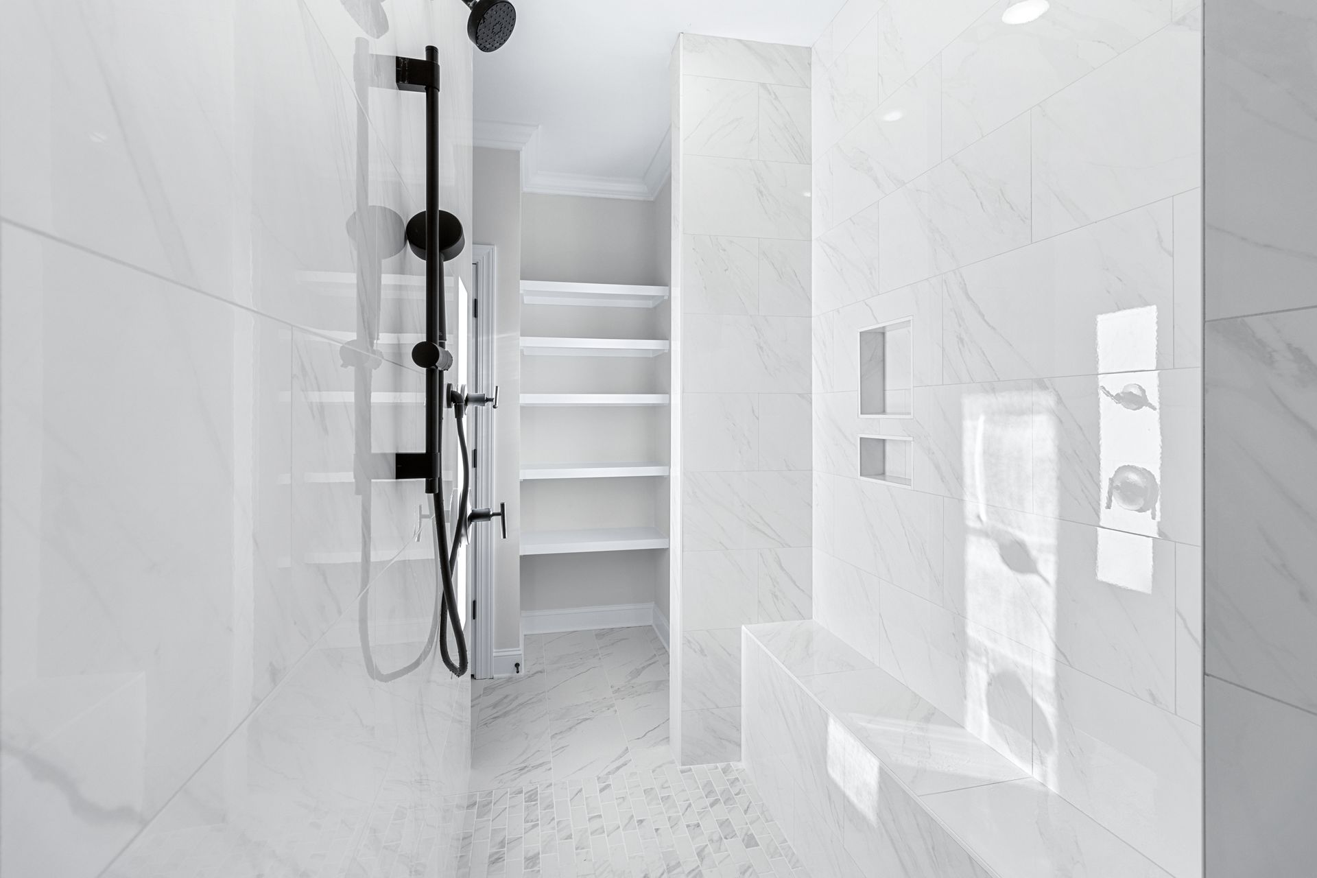 a bathroom with white tiles and a black shower head .