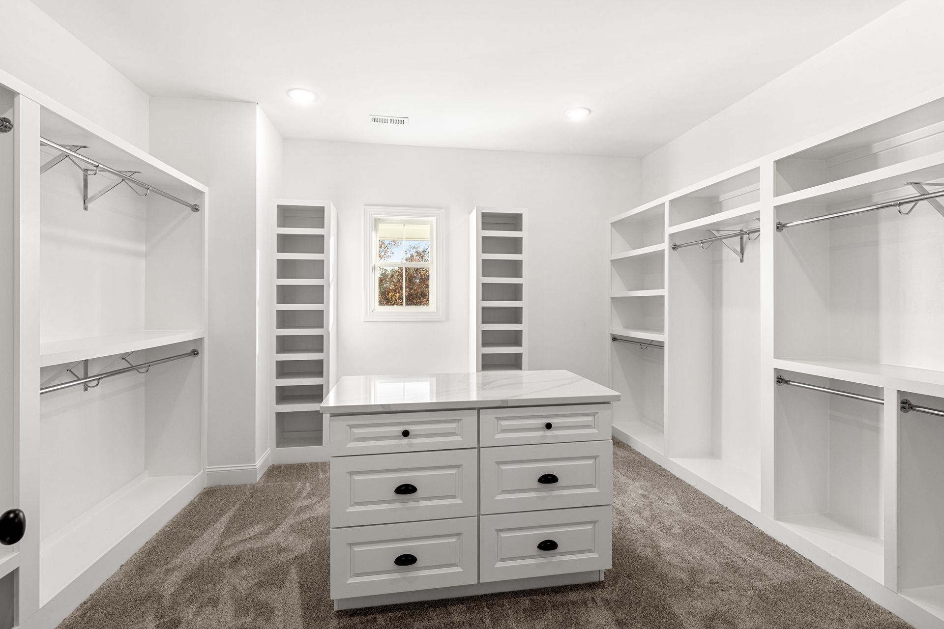 a large walk in closet with lots of shelves and drawers .