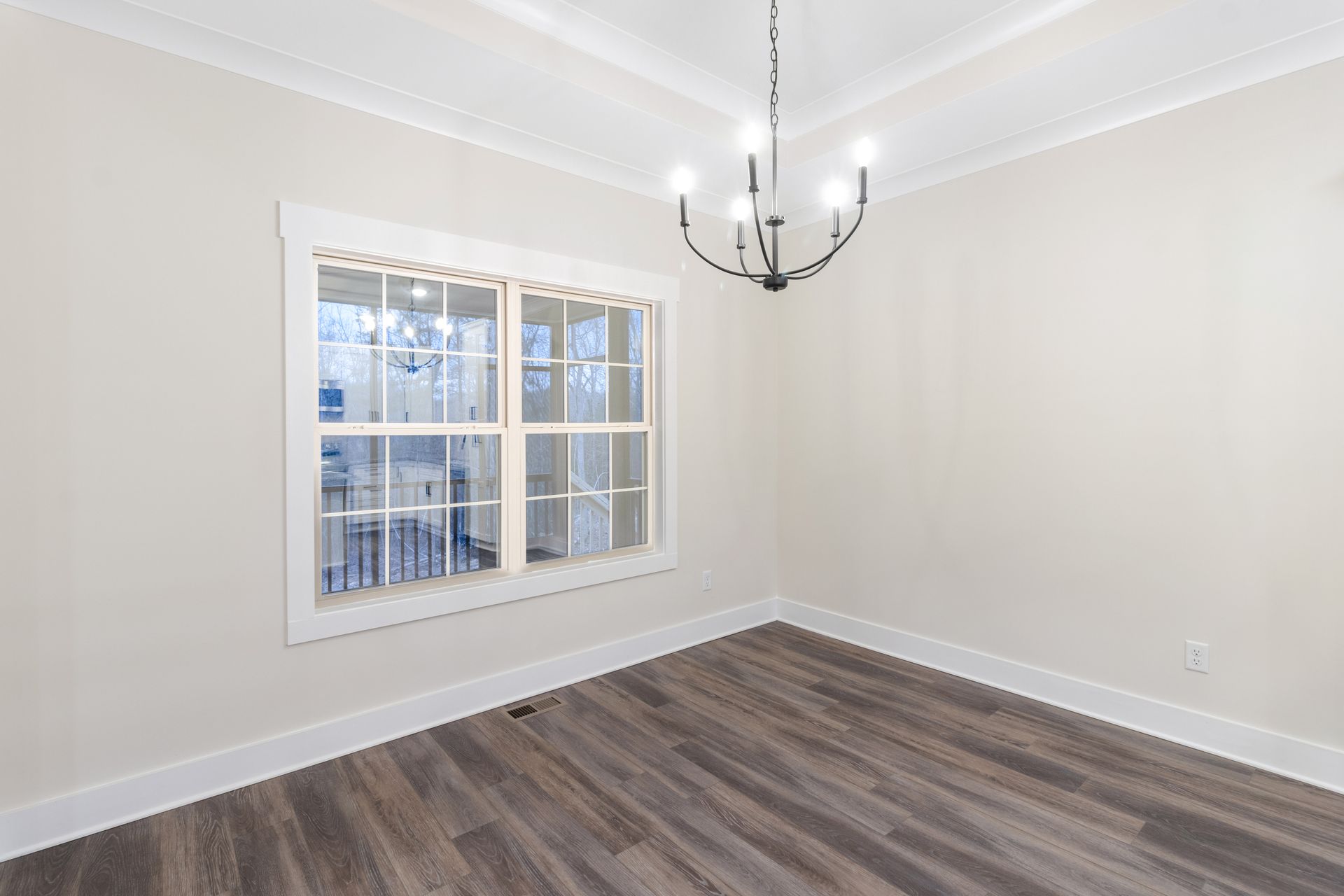 an empty dining room with a large window and a chandelier .