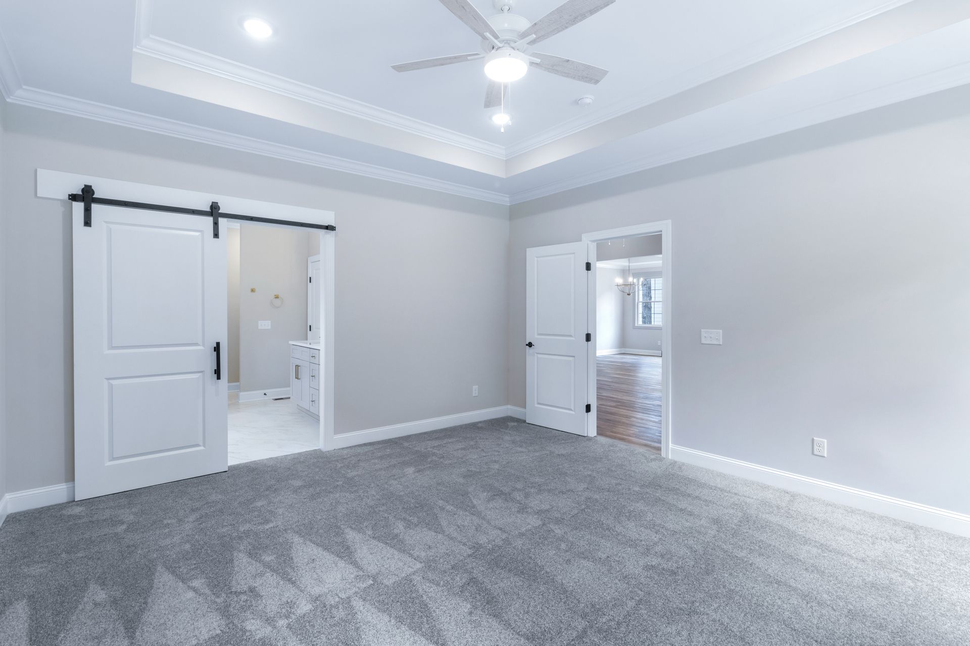 an empty bedroom with sliding barn doors and a ceiling fan .