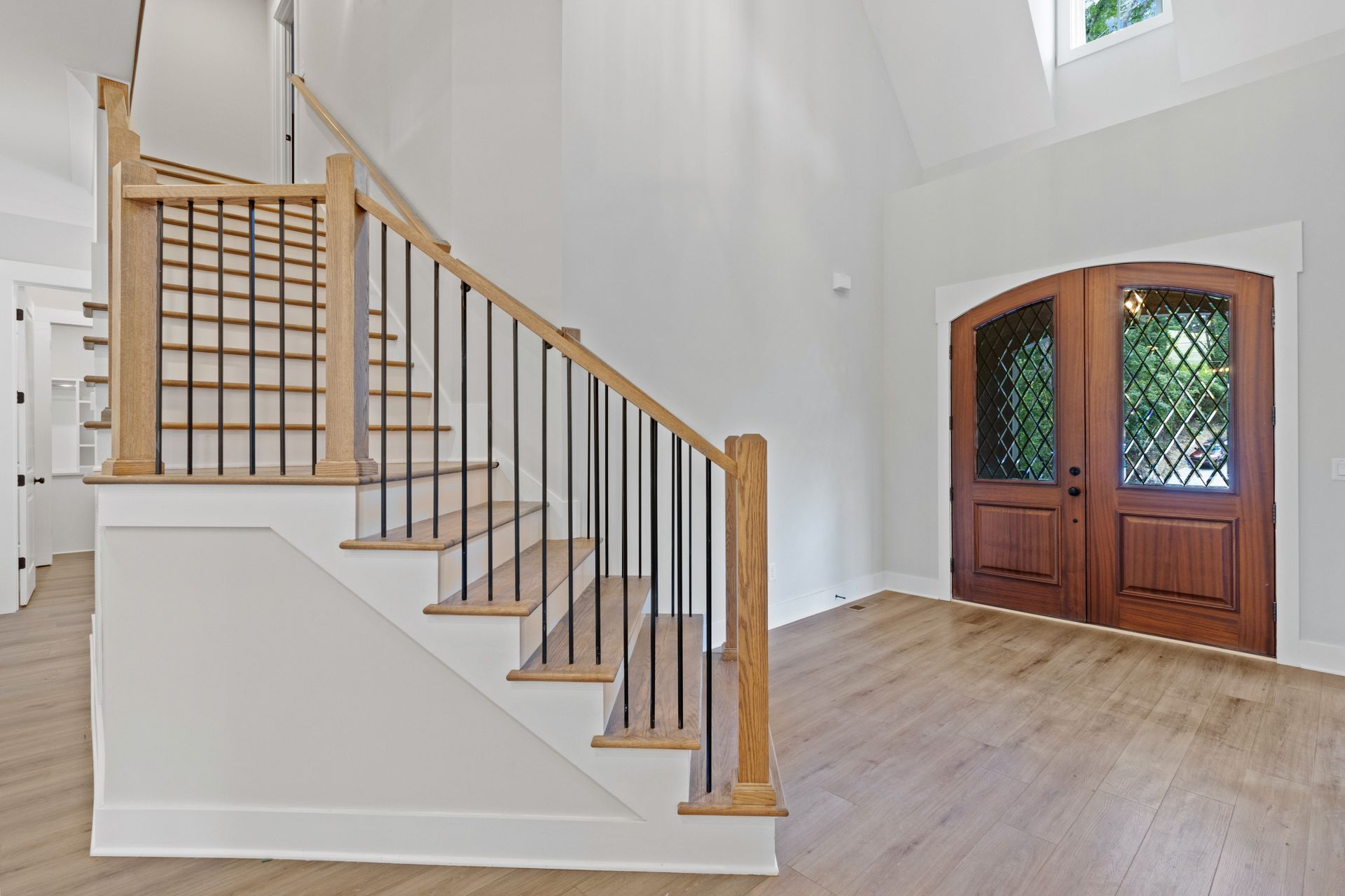 a staircase in a house with a wooden railing and a wooden door .