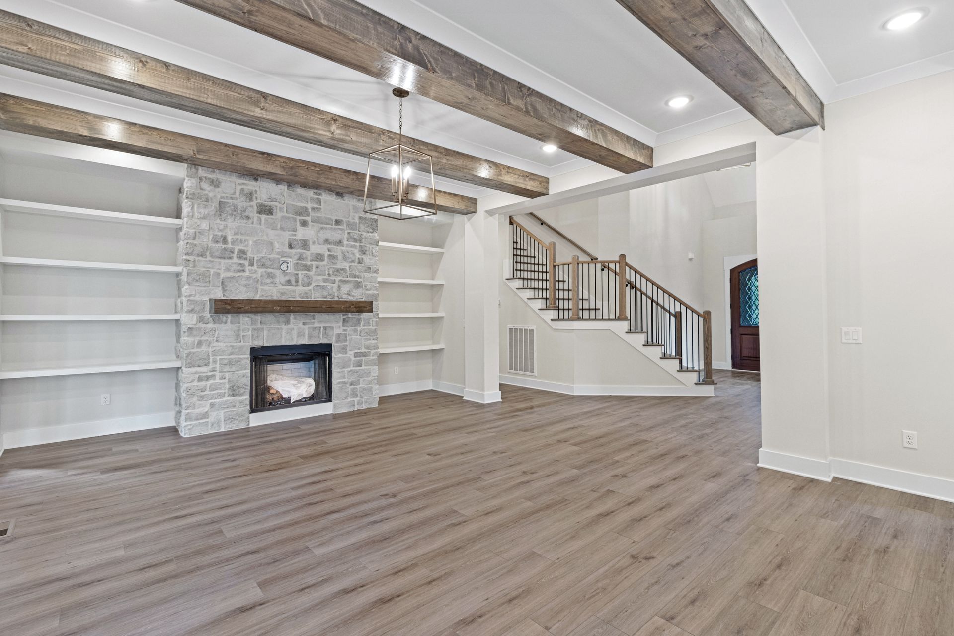 an empty living room with a fireplace and stairs .