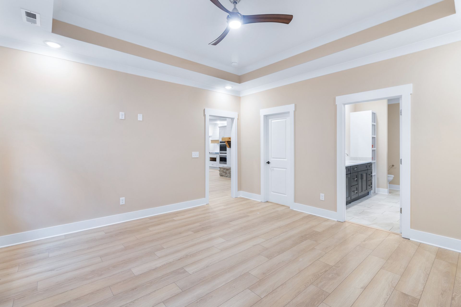an empty living room with hardwood floors and a ceiling fan .