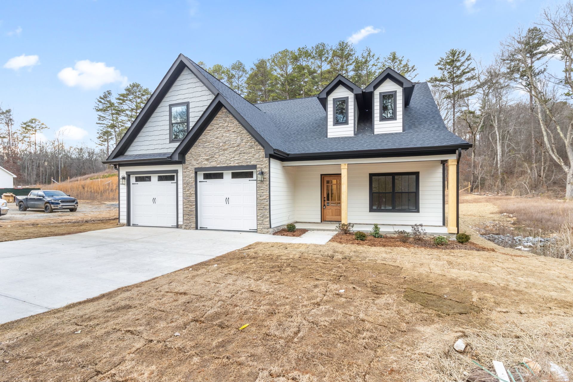 a white house with a black roof is sitting on top of a dirt field .