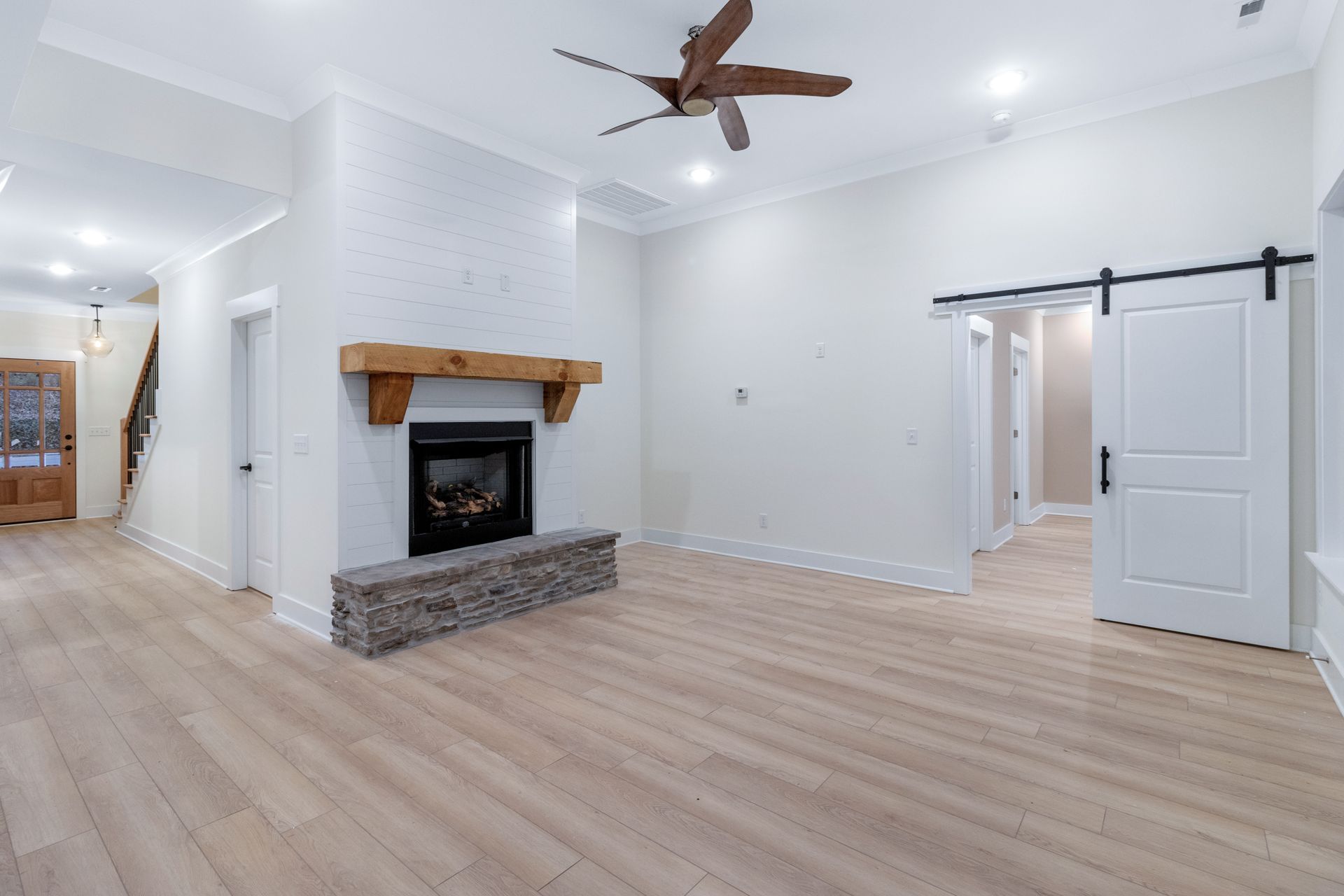An empty living room with a fireplace and ceiling fan.