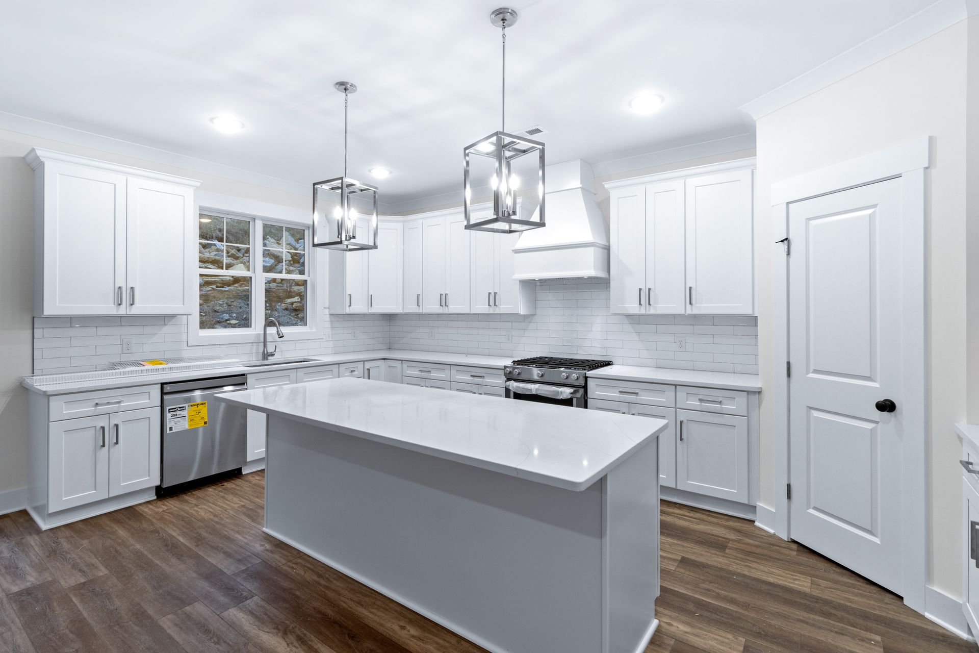 a kitchen with white cabinets , stainless steel appliances , and a large island .
