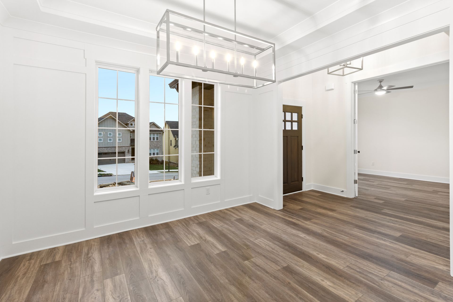 An empty living room with hardwood floors and a chandelier.