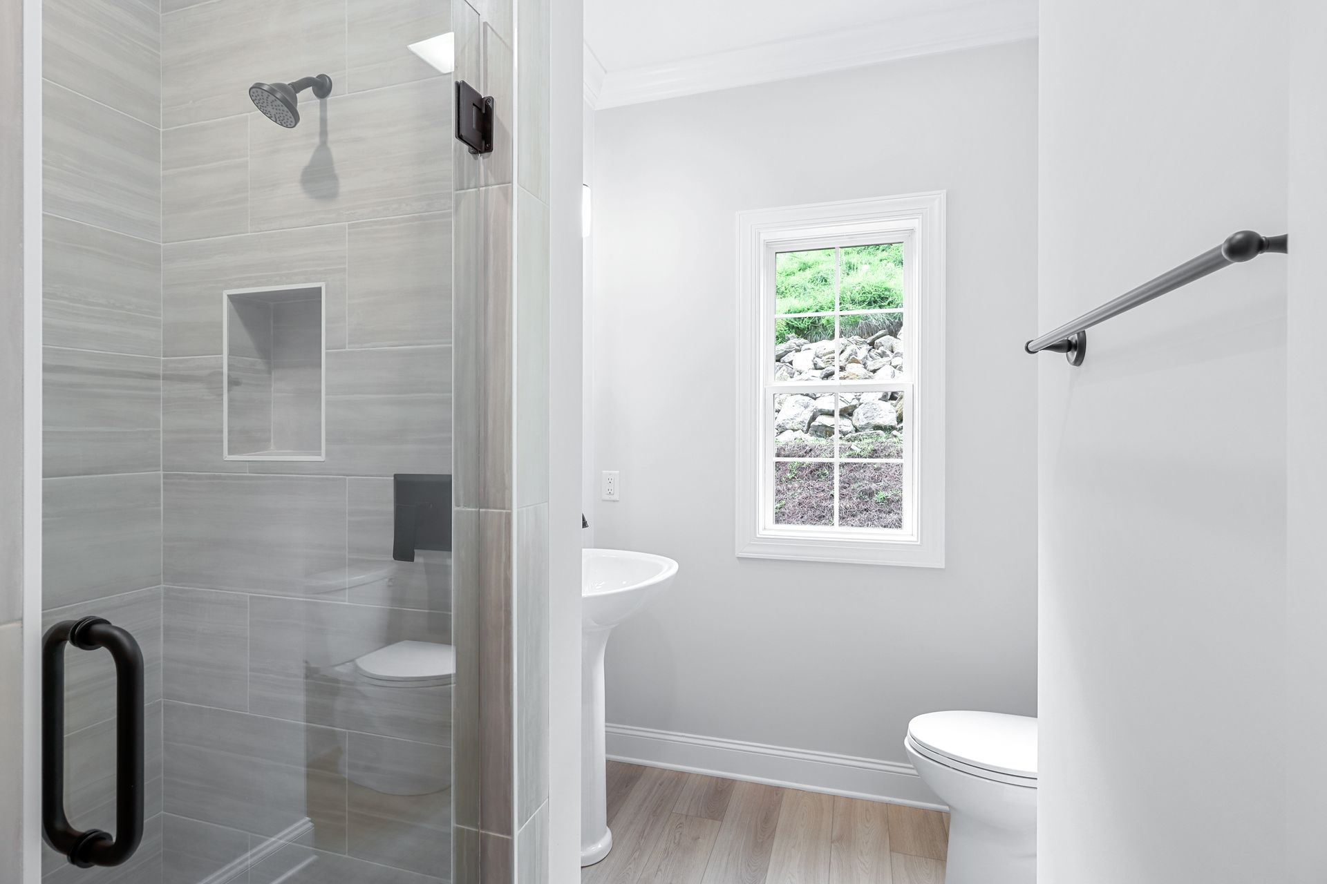 a bathroom with a walk in shower , toilet , sink and window .