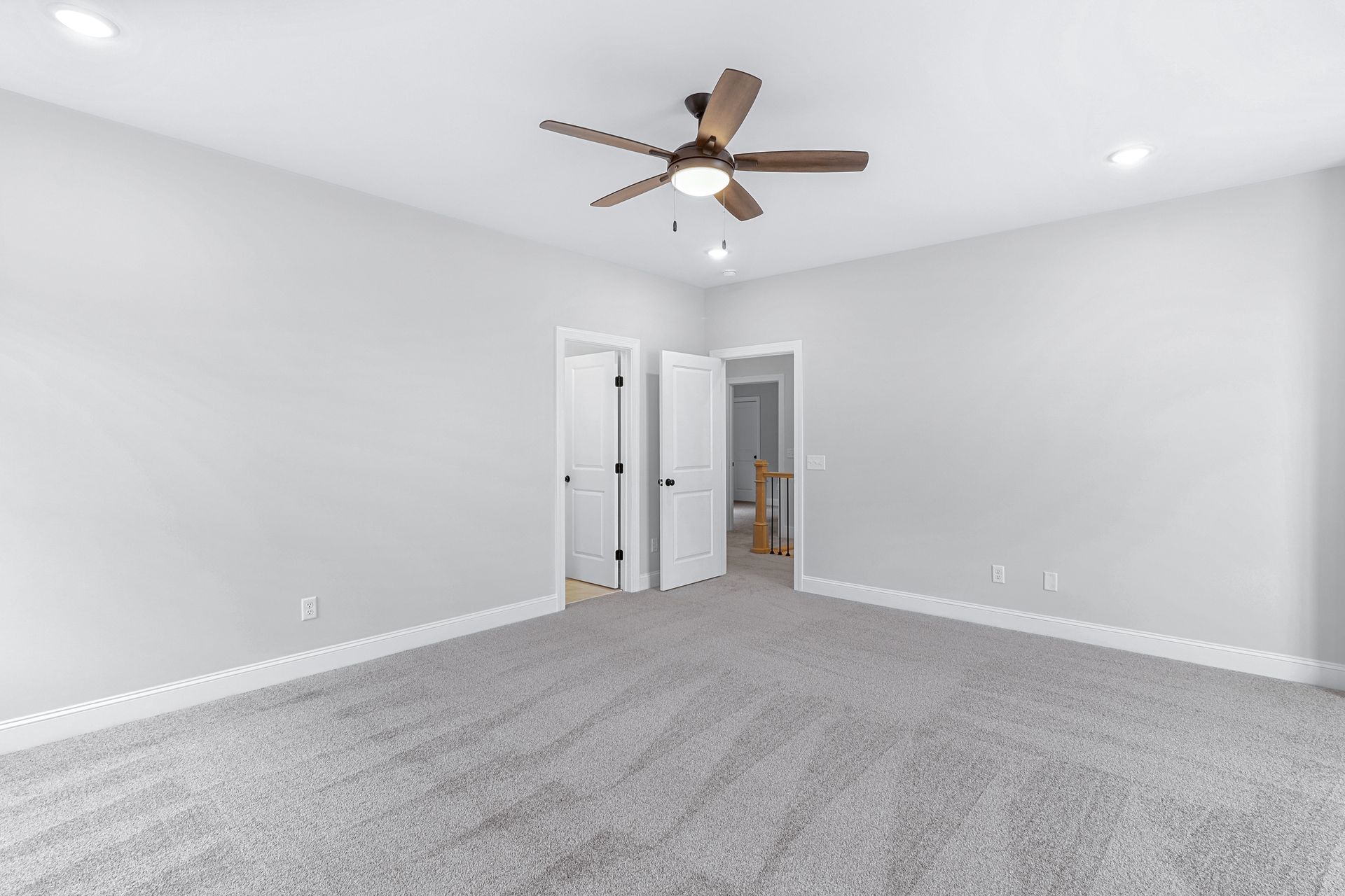 an empty bedroom with a ceiling fan and a gray carpet .