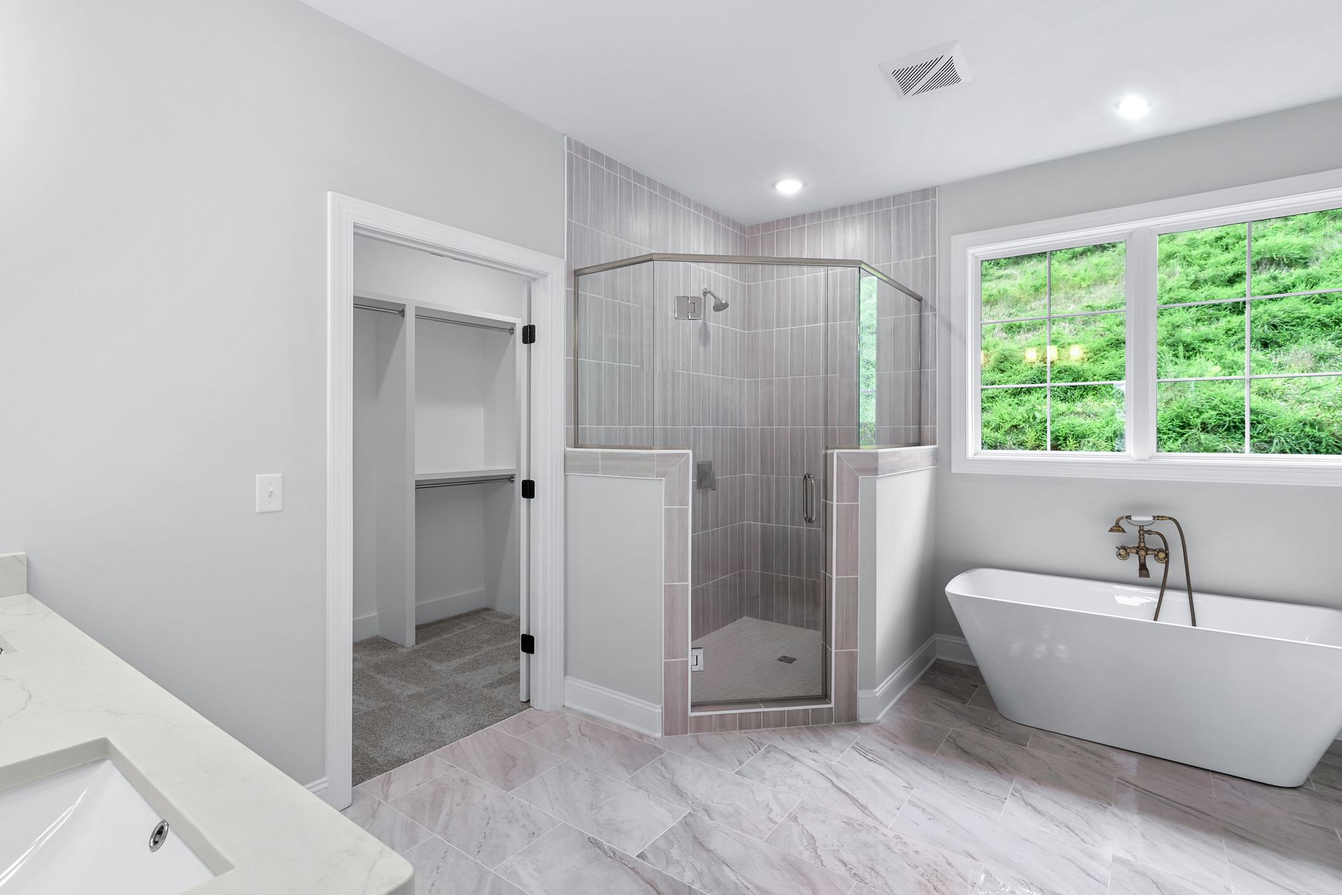 a bathroom with a tub , sink , walk in closet and shower .