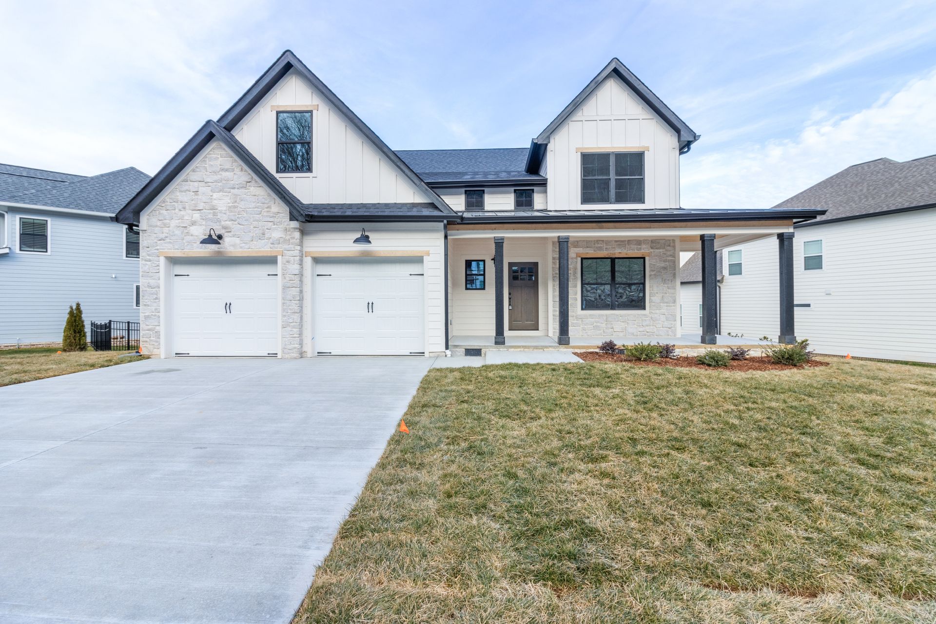 A large white house with two garages and a concrete driveway.